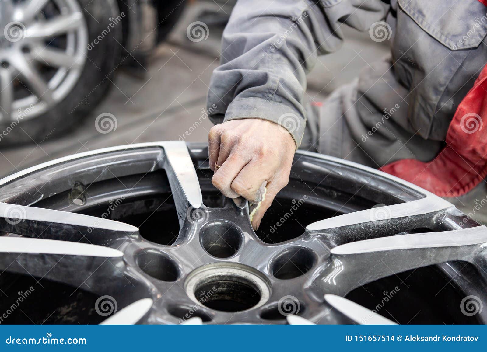 master body repair man is working on preparing the surface of the aluminum wheel of the car for subsequent painting in the