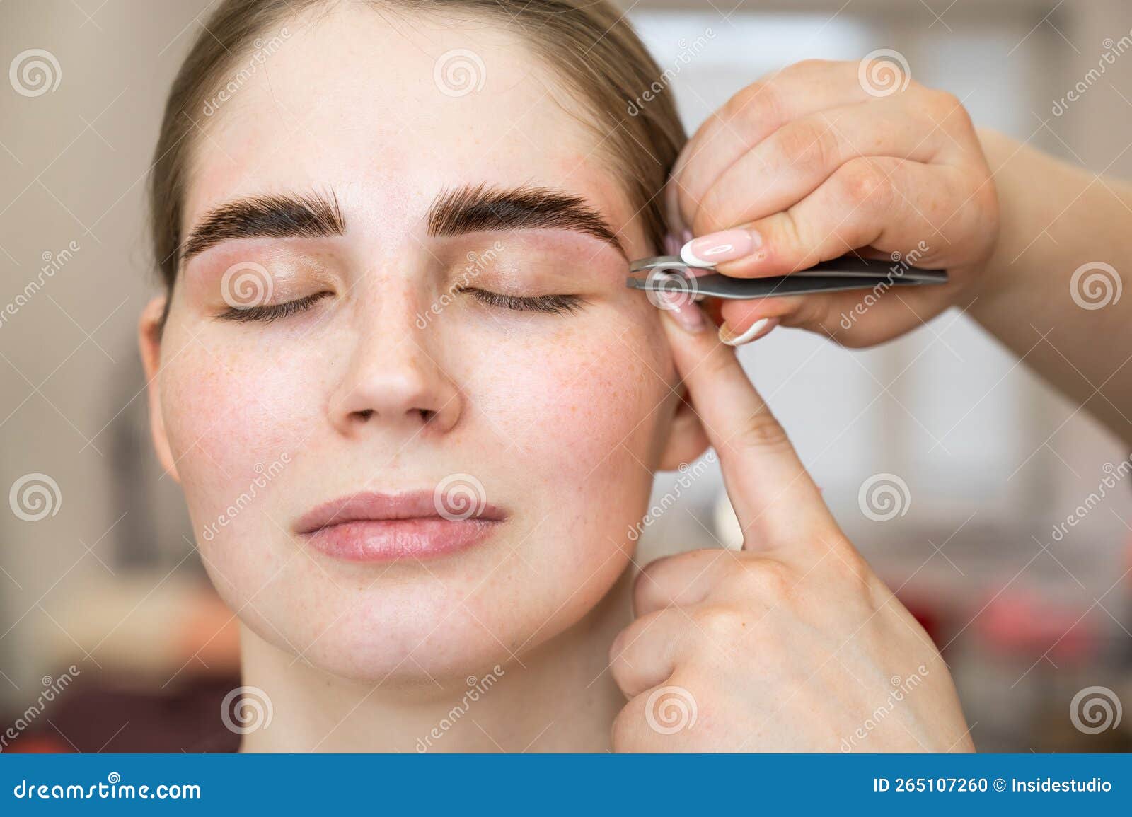 The Master Makes the Client Eyebrow Correction with Tweezers. Stock