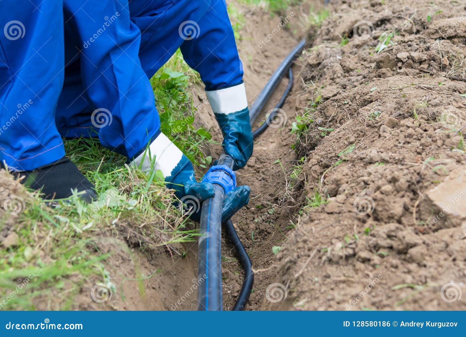 The Master Puts a Black Pipe into the Ground, Closeup Stock Photo