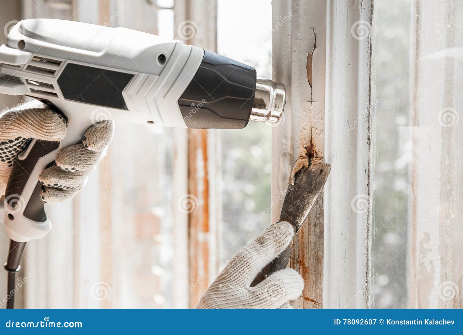 Master Removes Old Paint from Window with Heat Gun and Scraper. Closeup
