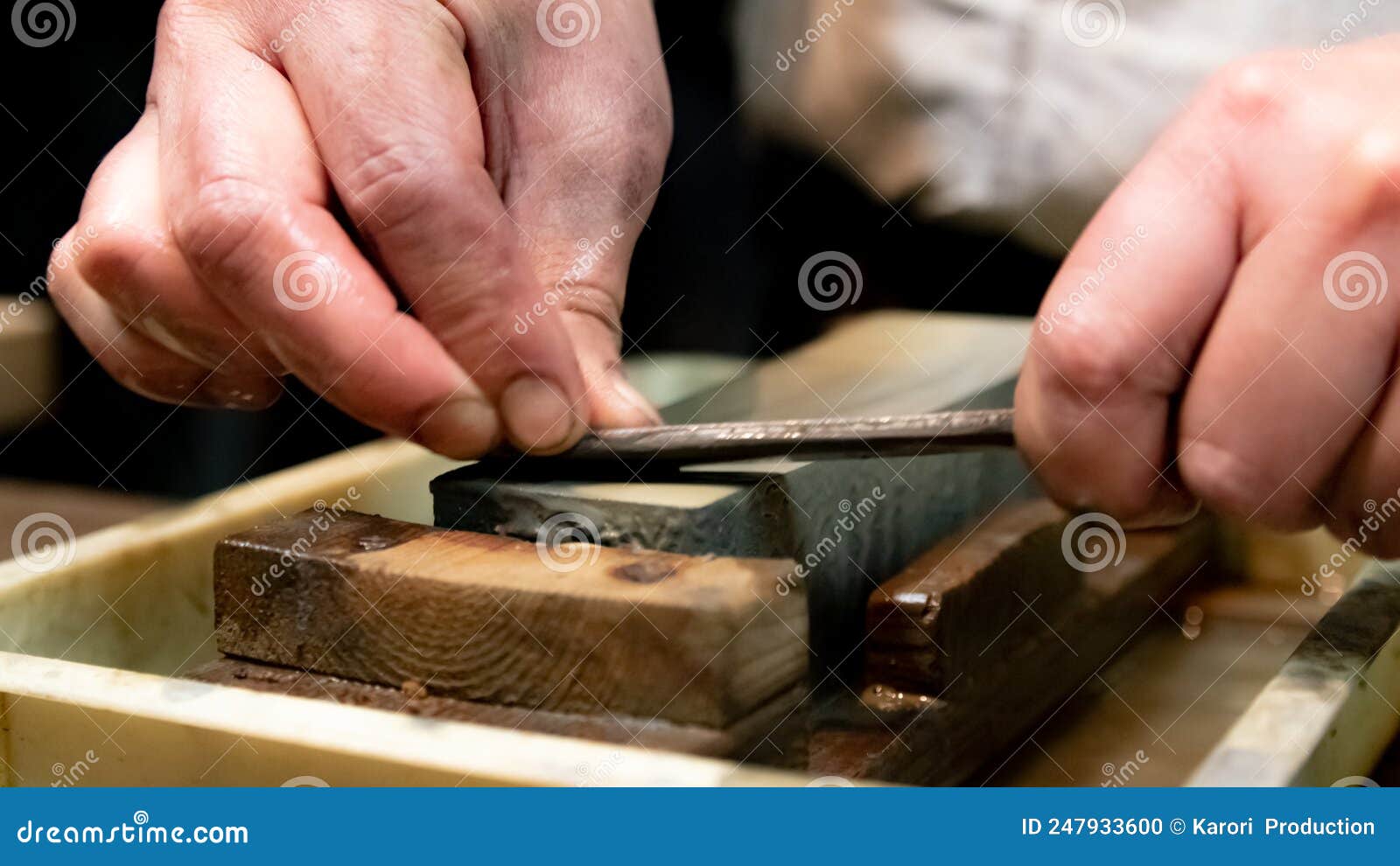 master swordsmith is sharpening knife on grindstone with water