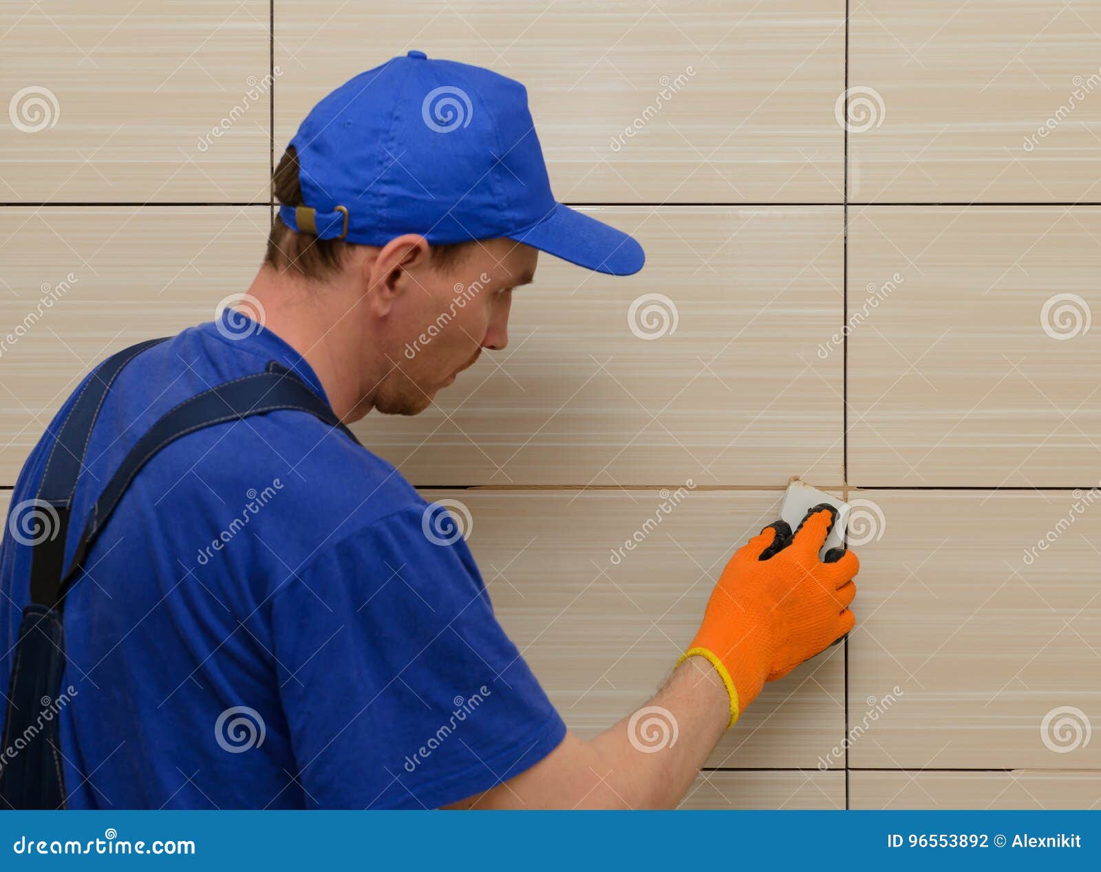 Master Tiler Glues Wall White Ceramic Tiles. The Process Of Grouting