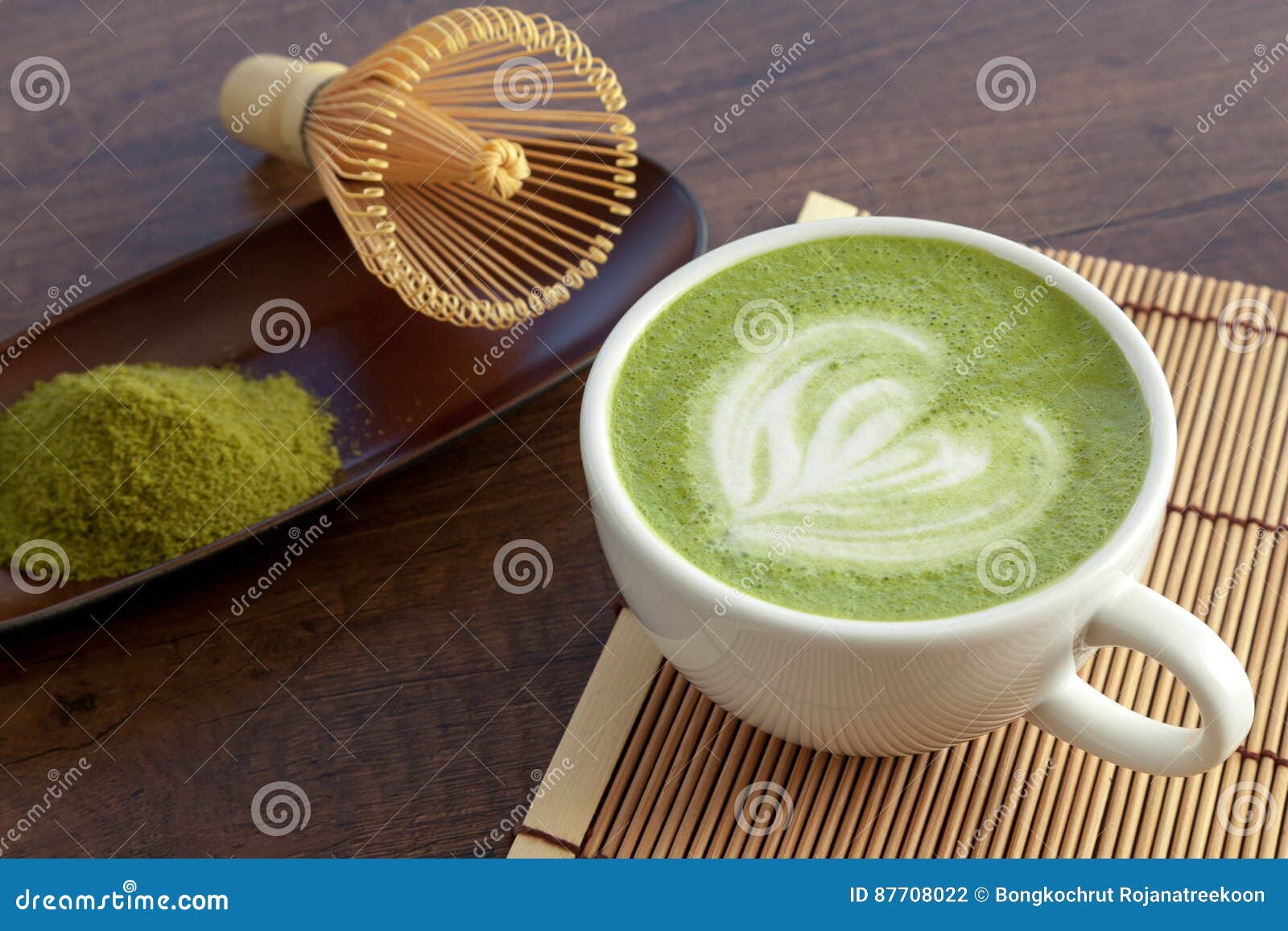 matcha latte art heart  on top on wooden table with some gr