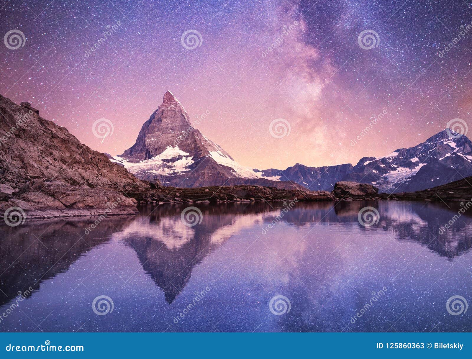 matterhorn and reflection on the water surface at the night time. milky way above matterhorn, switzerland.