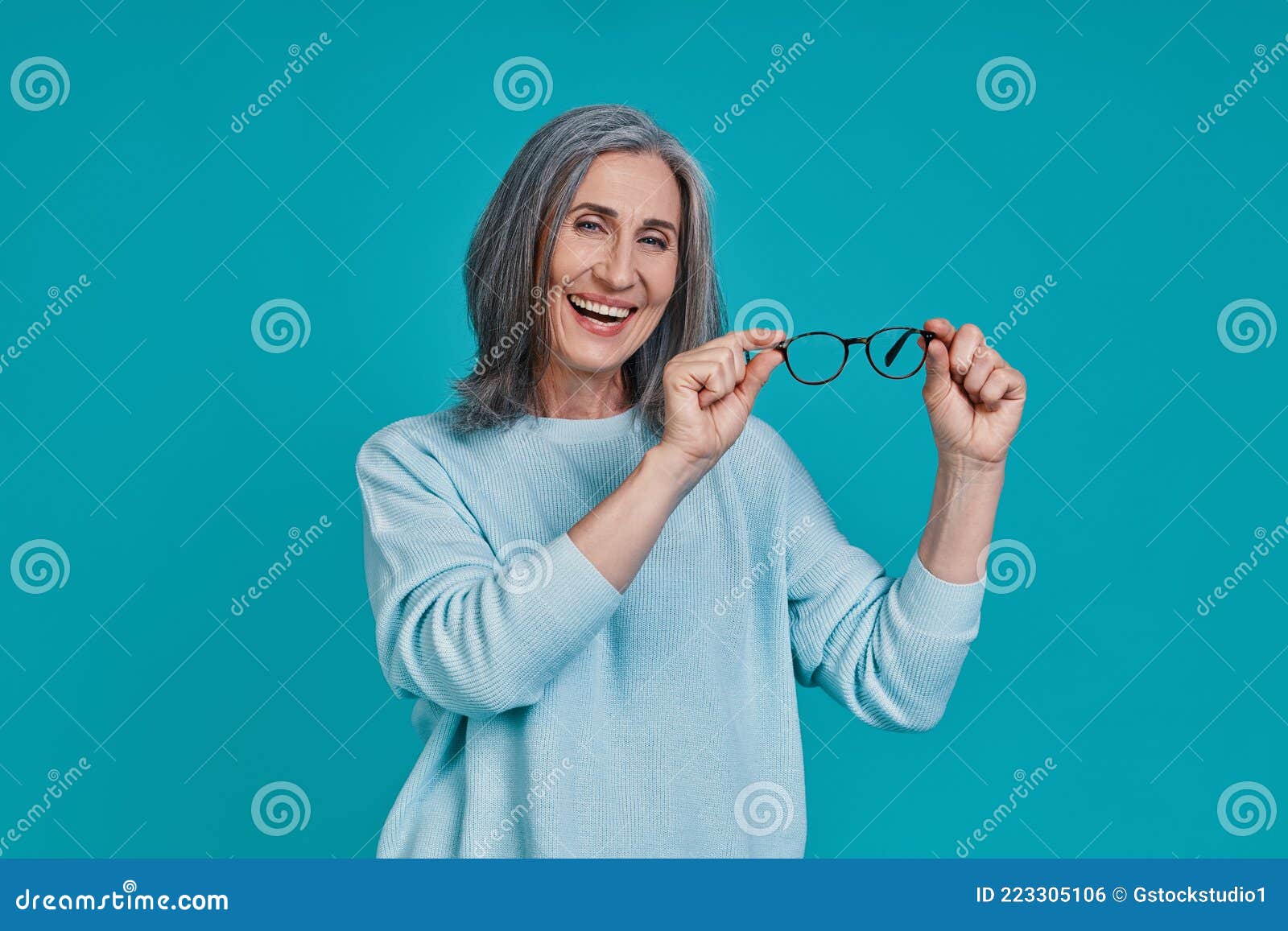 Mature Beautiful Woman Looking At Camera And Smiling While Standing Against Blue Background