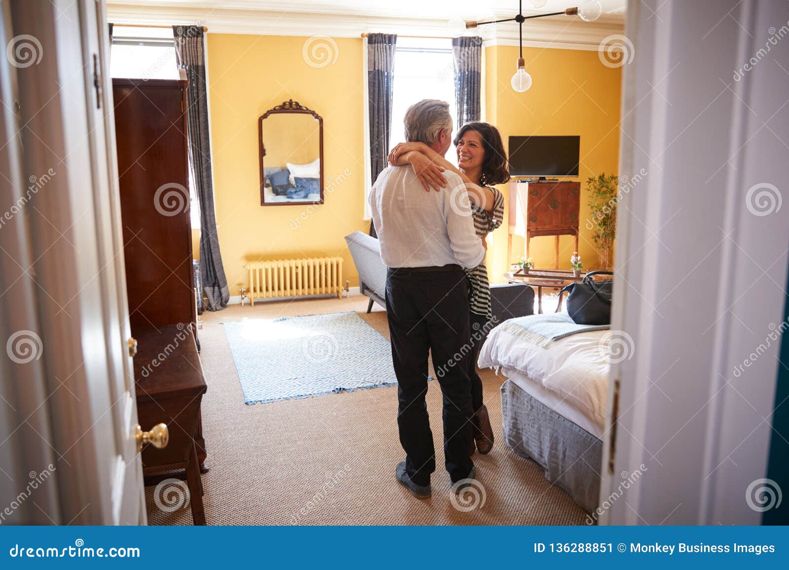 Mature Couple Embrace Looking At Each Other In Hotel Room Stock Image