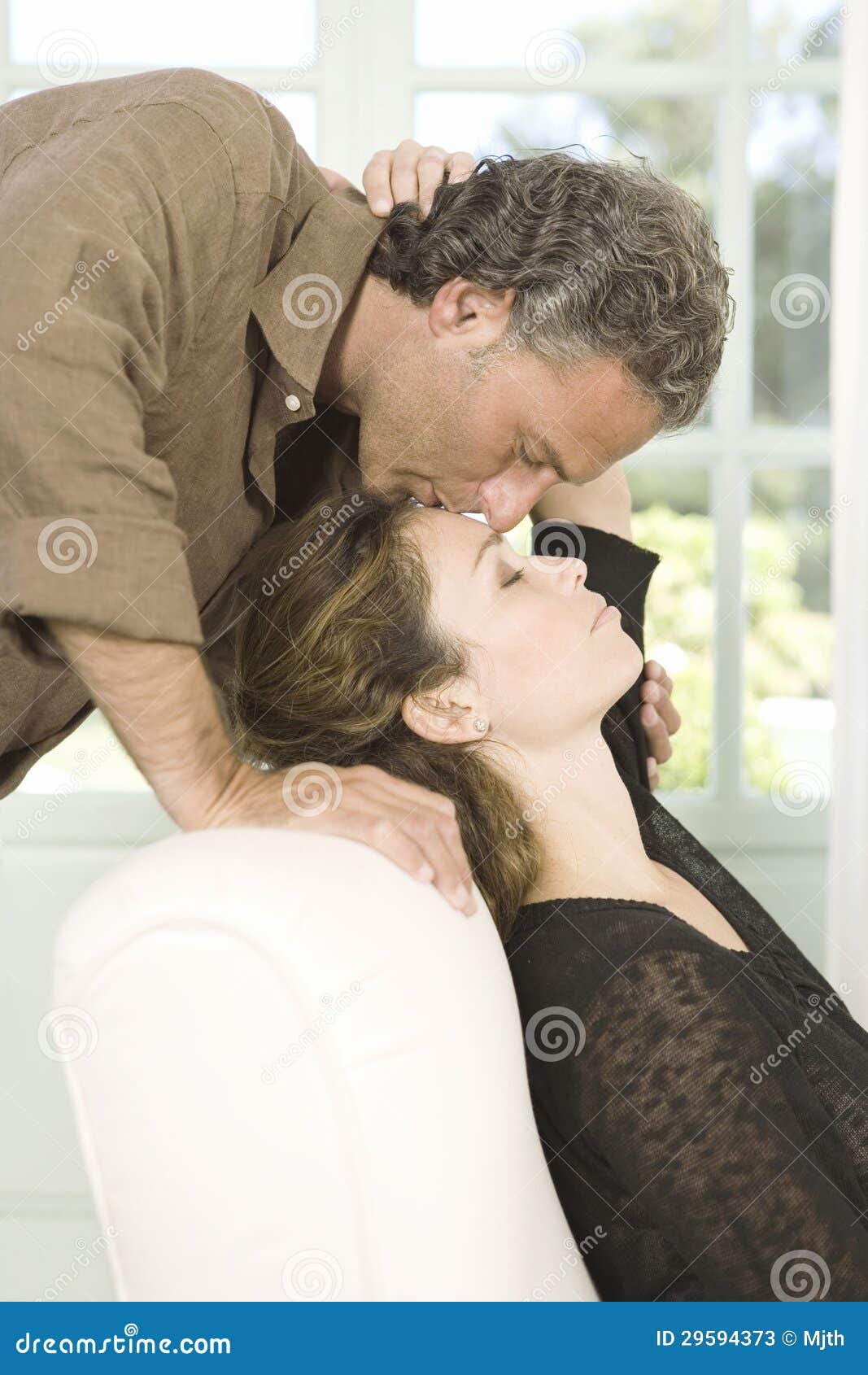 Mature Couple Kissing In Living Room Stock Photos