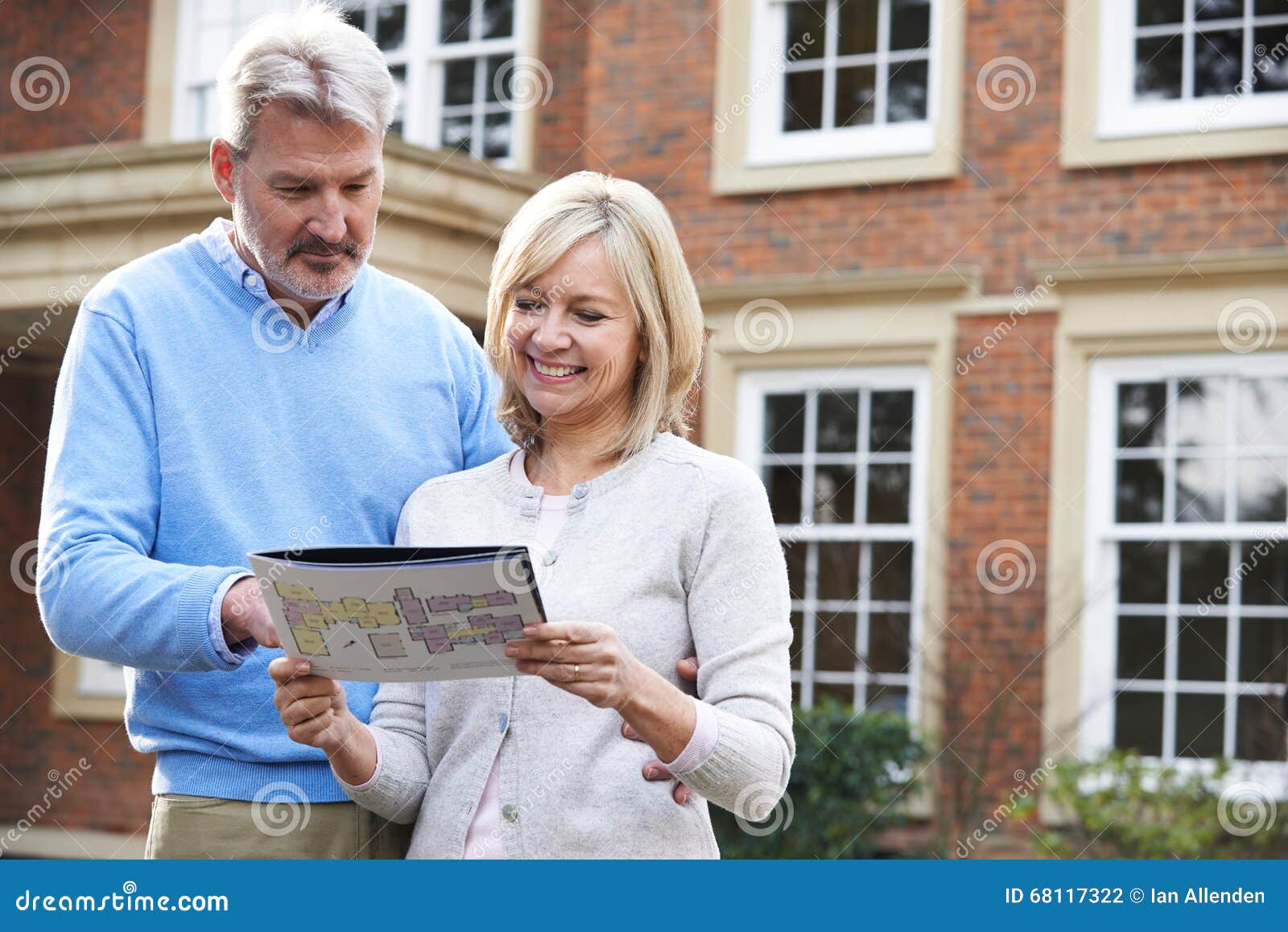 mature couple standing outside house looking at property details