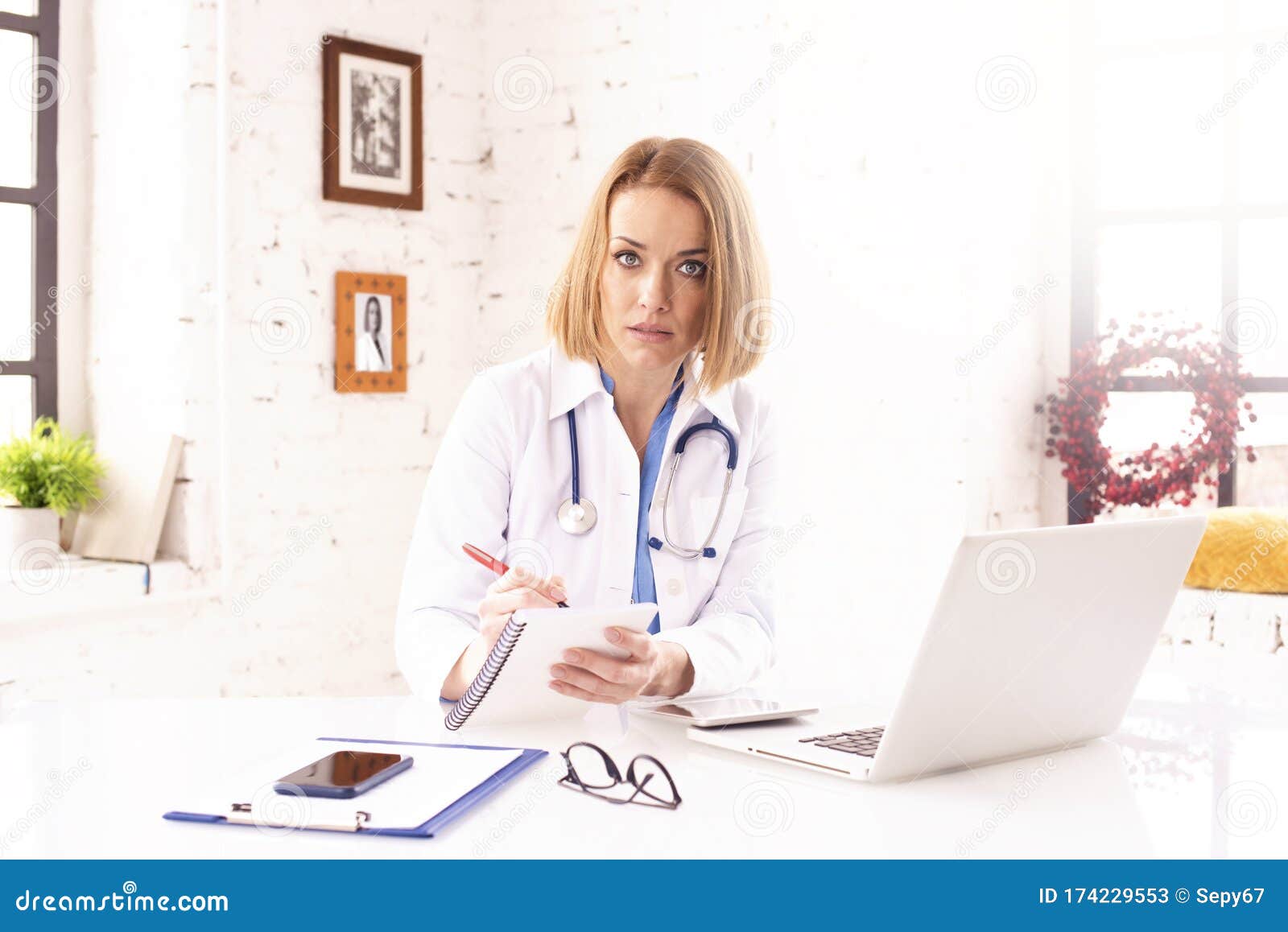 mature female doctor doing making notes while working in doctor`s office
