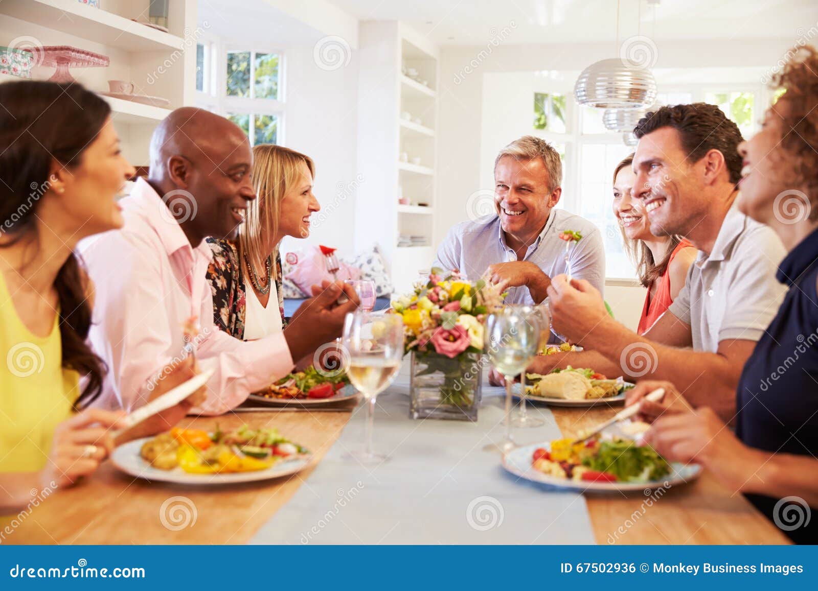 mature friends sitting around table at dinner party