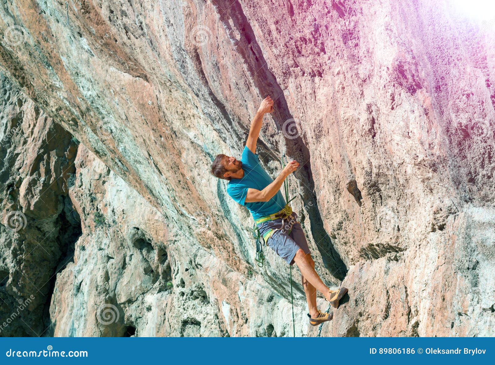 Mature Male Climber Making Risky Move on Rock Sun Shining Stock Photo