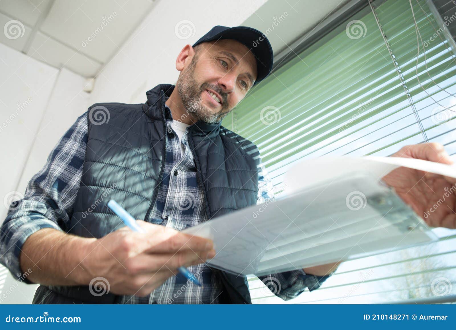 mature male contractor looking at paperwork on clipboard