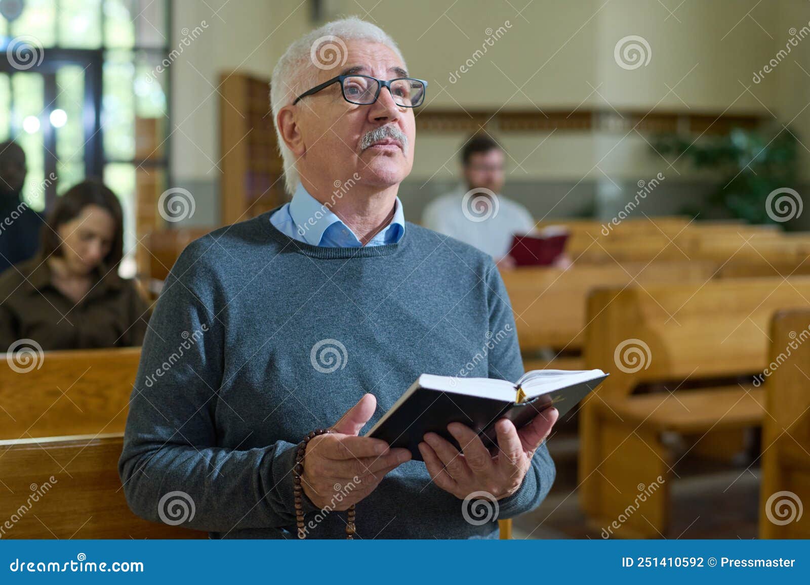 Mature Man With Grey Hair Holding Open Bible While Listening To 