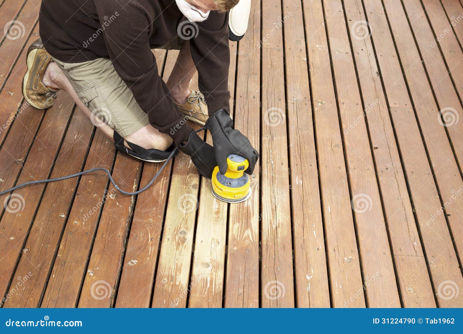 mature man performing maintenance on home wooden deck