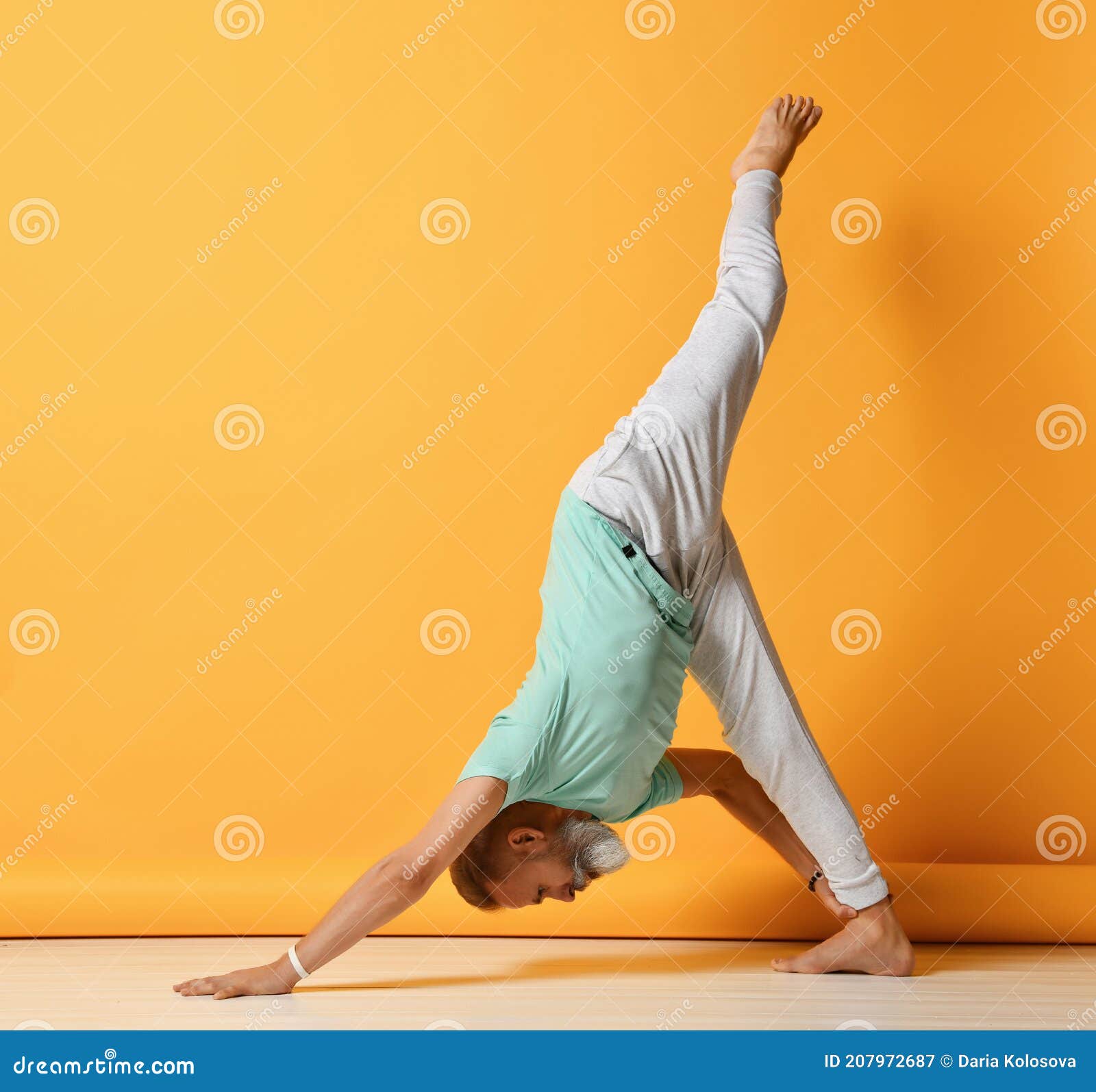 mature man standing inverted pyramid yoga pose active bearded grey haired balancing one leg hand stretching twine 207972687