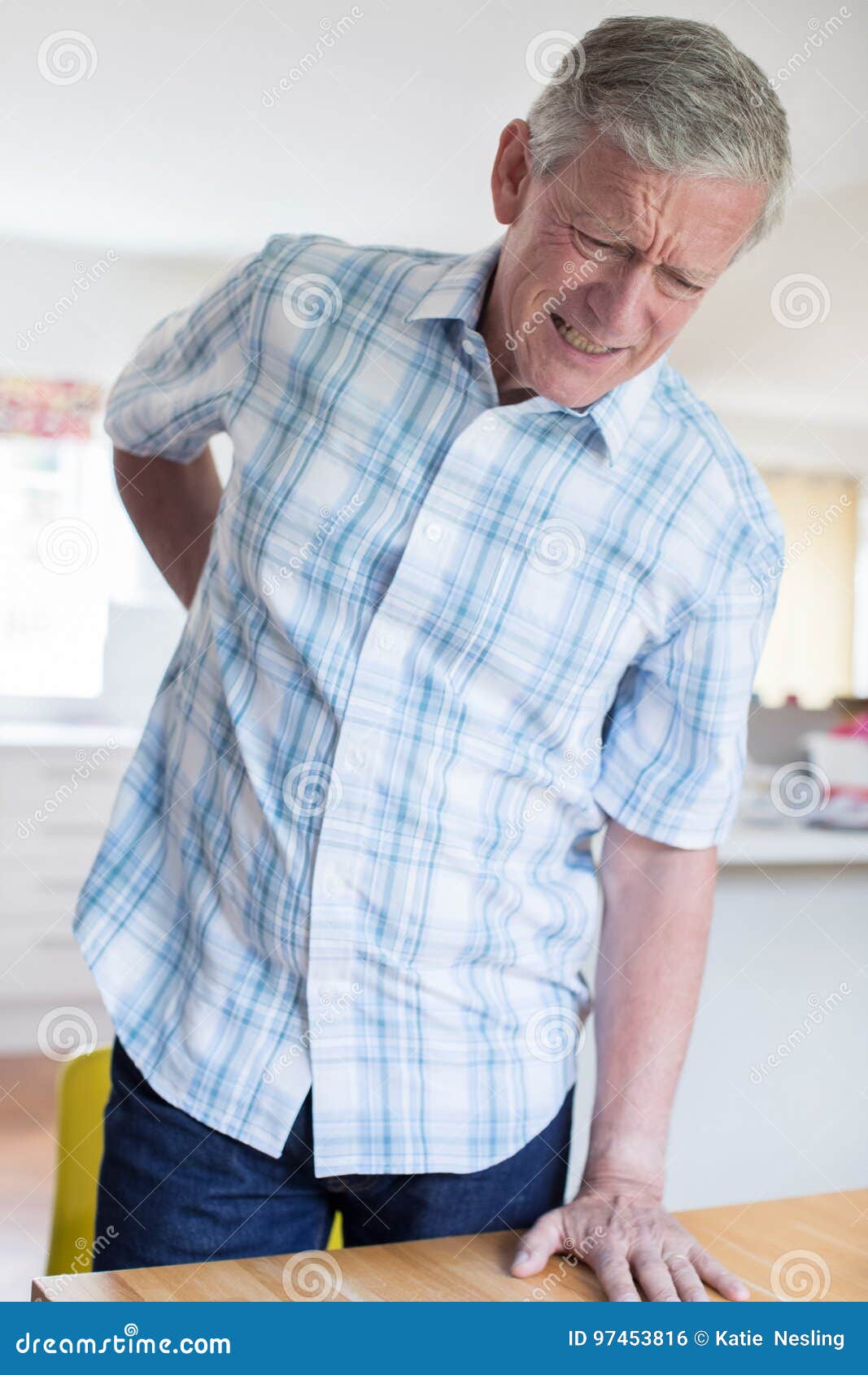 Mature Man Suffering From Backache Whilst Getting Out Of Chair A