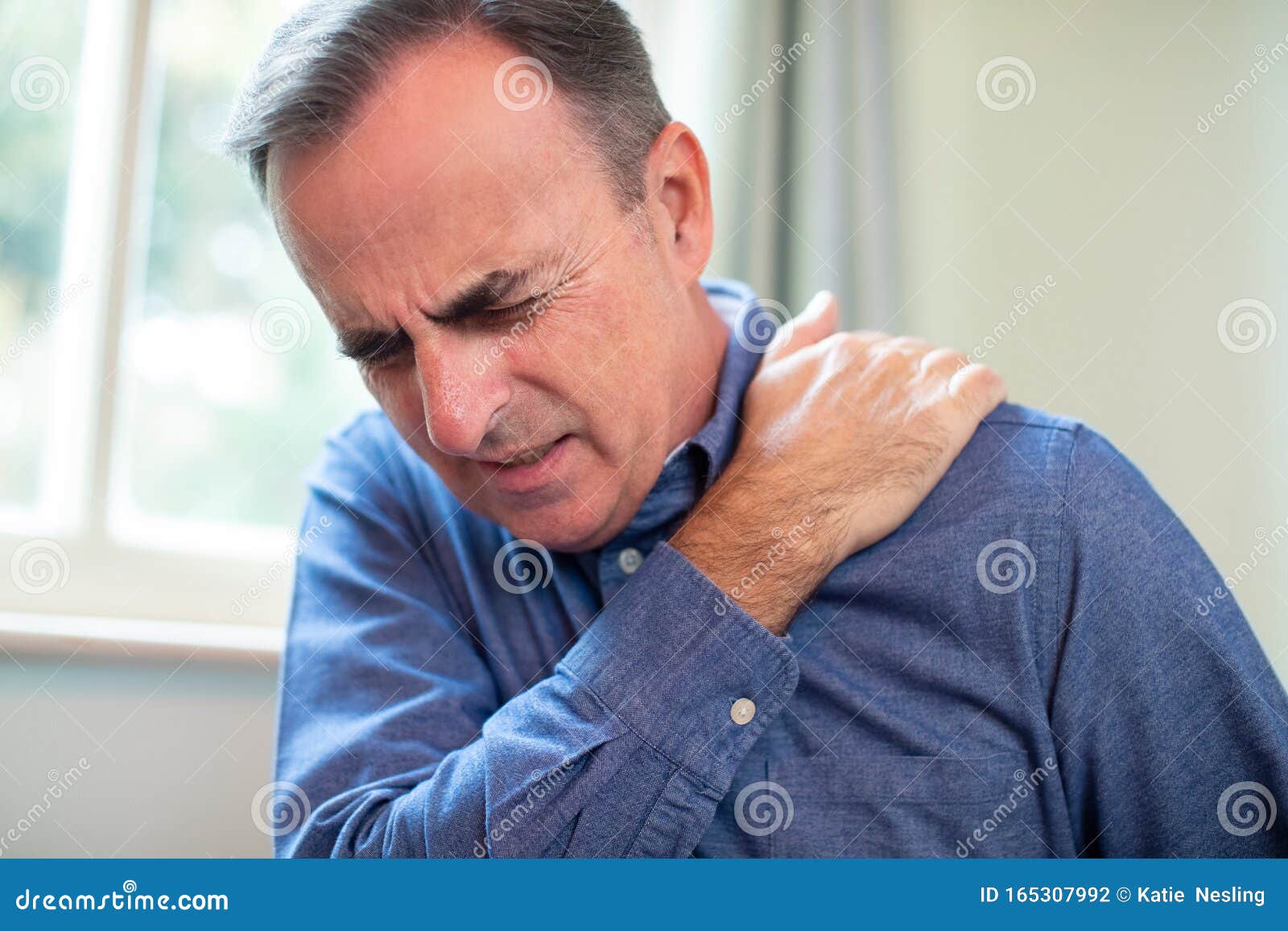 mature man suffering with trapped nerve in shoulder at home