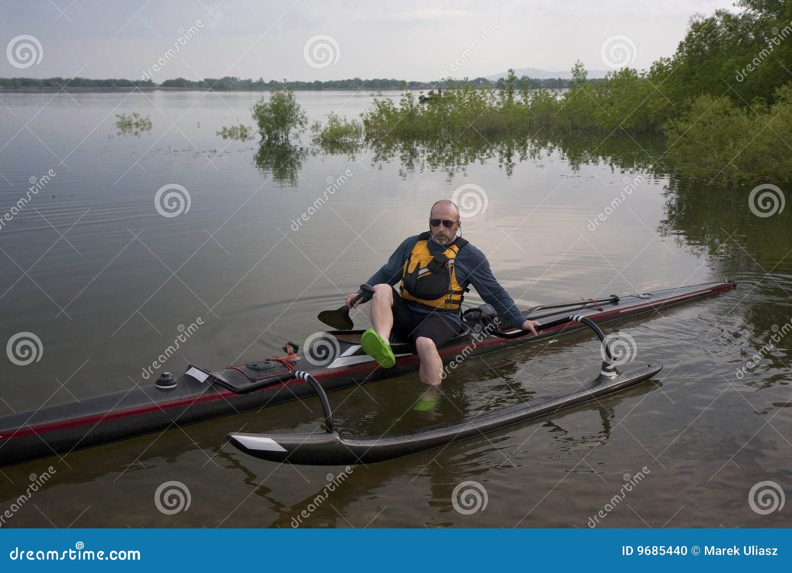  black (carbon fiber) racing outrigger canoe, calm lake, springtime