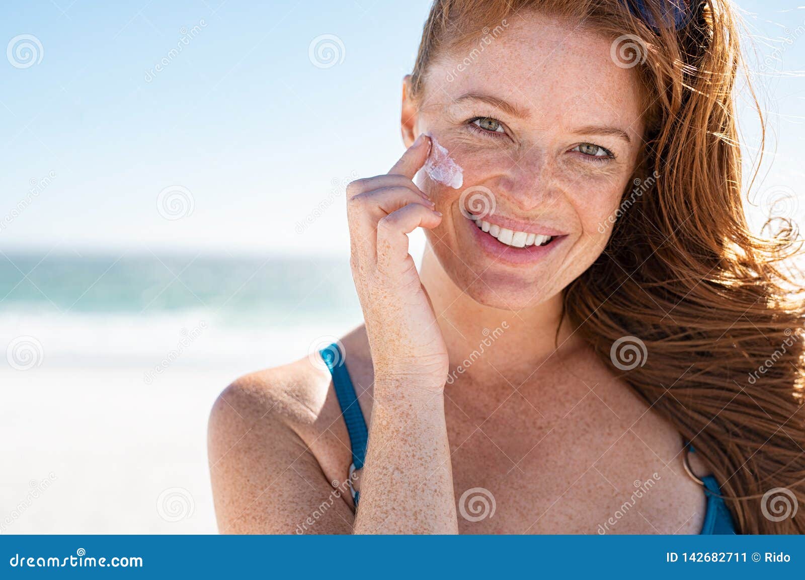 mature woman applying sunscreen on face