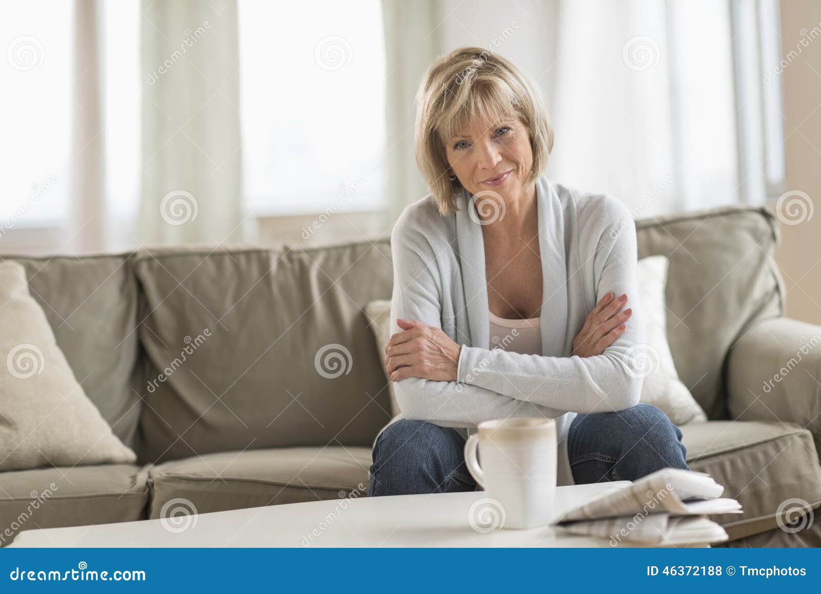 mature woman with arms crossed sitting on sofa