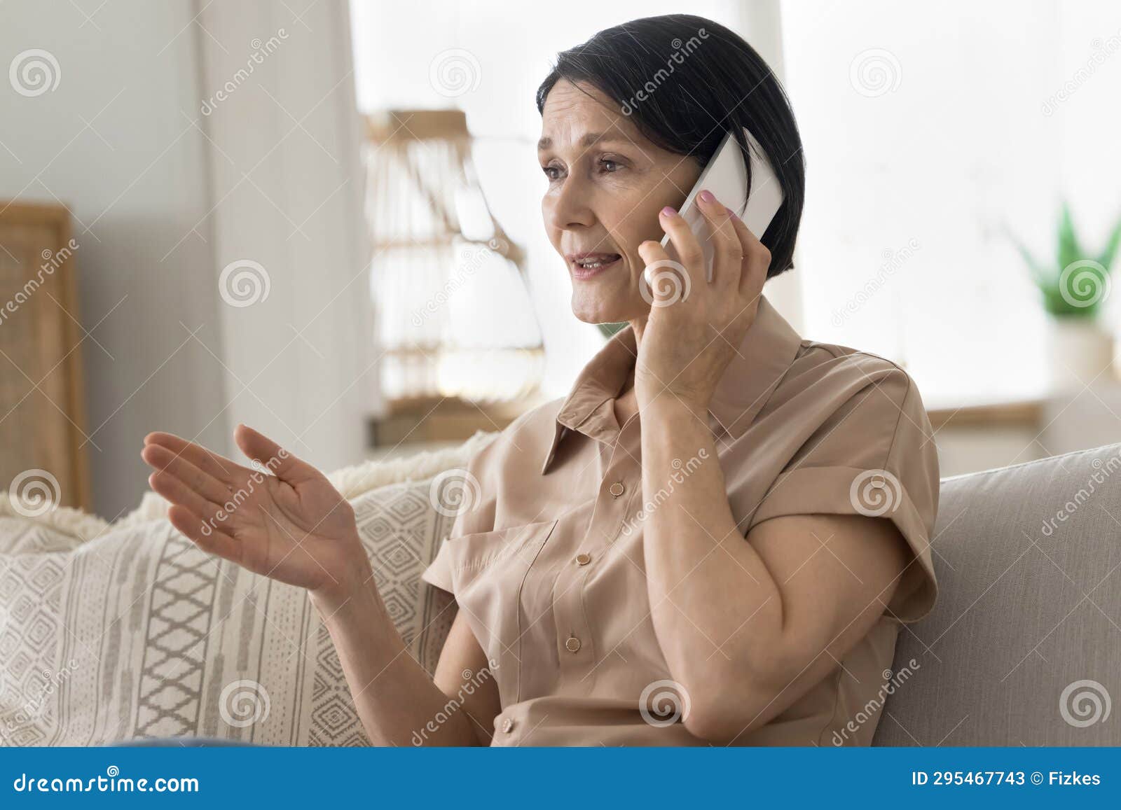 mature woman blab on cellphone seated on couch
