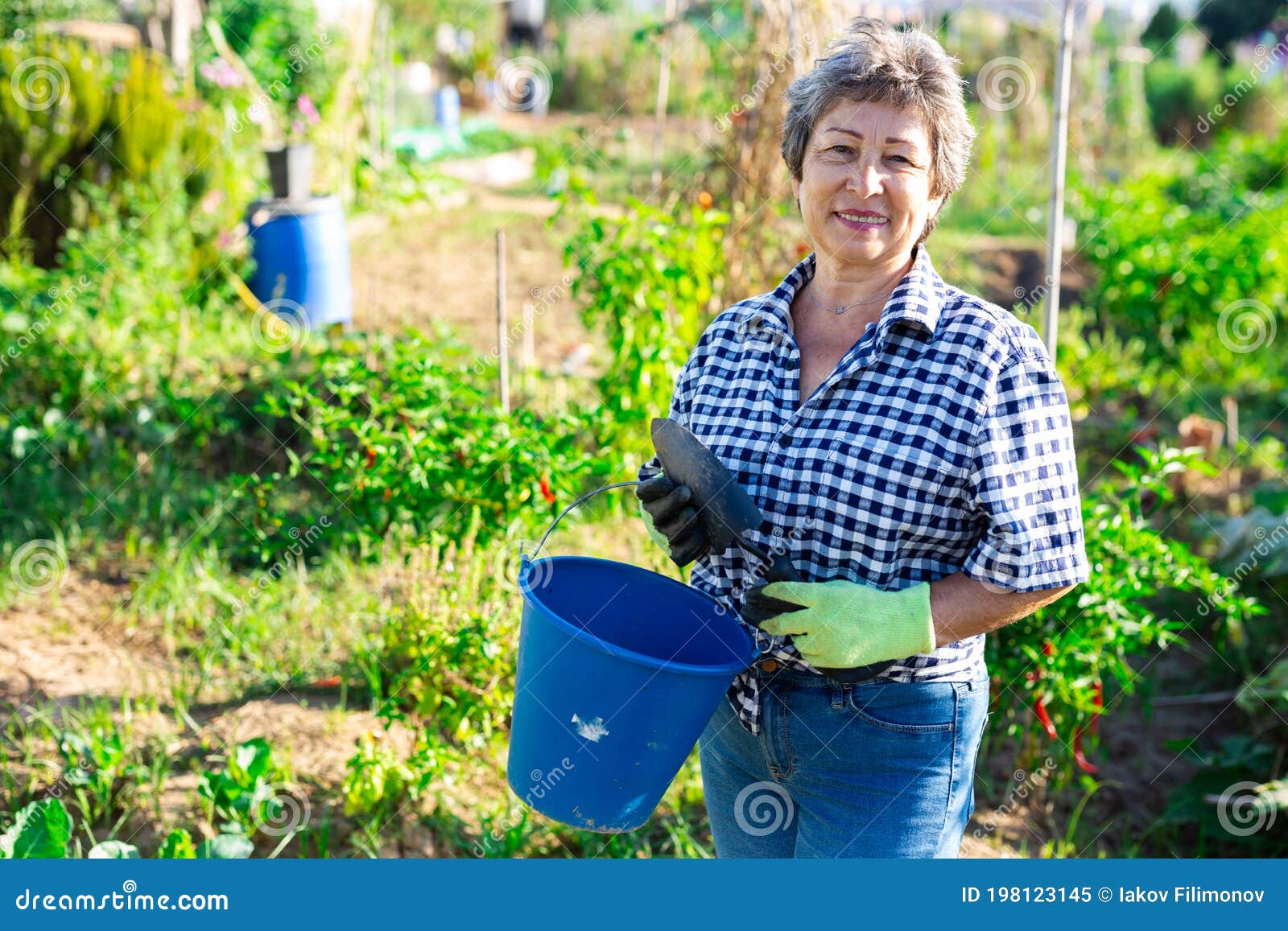 mature woman having horticultural instruments in garden on day