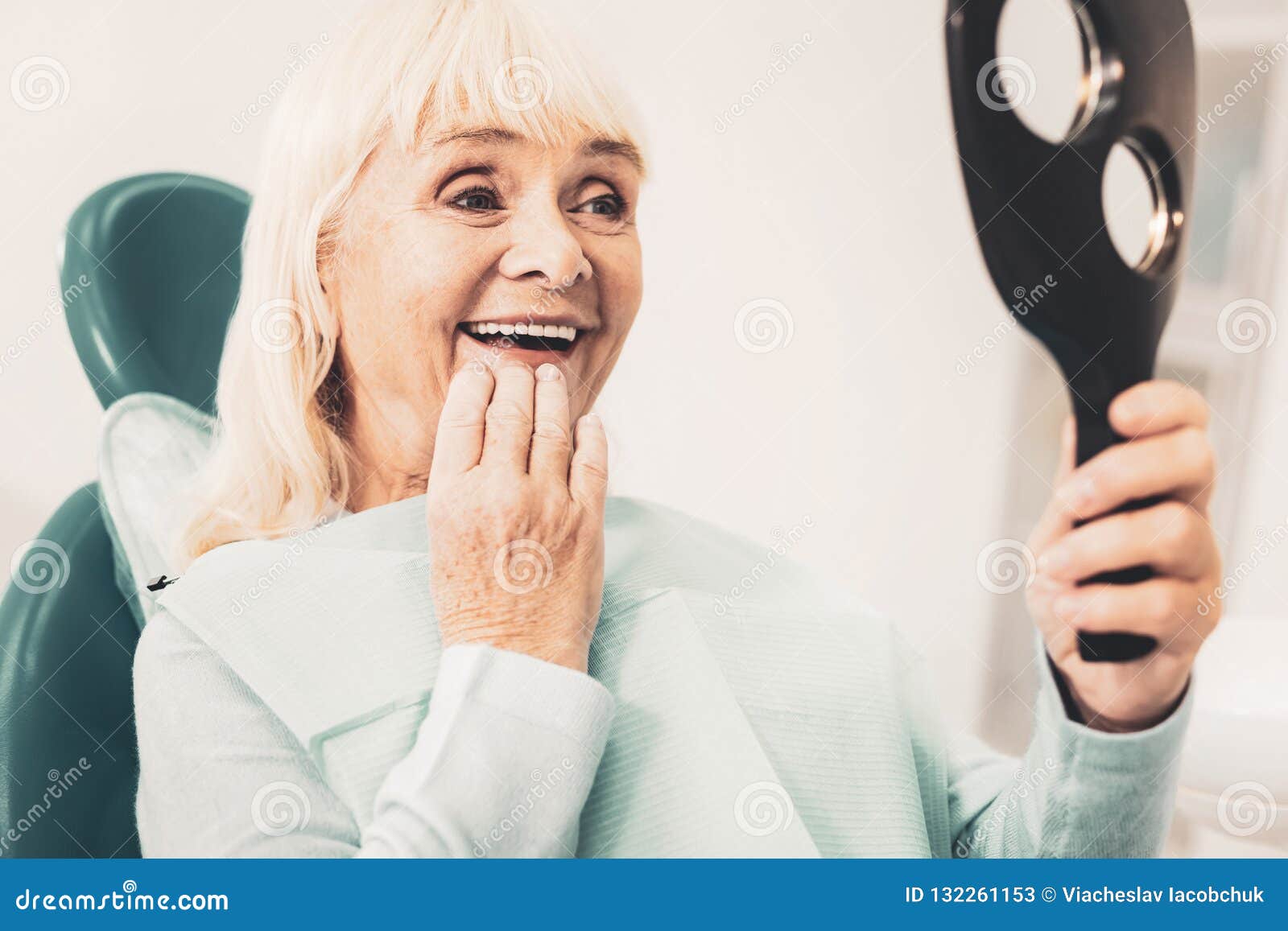 mature woman with mirror looking at her denture