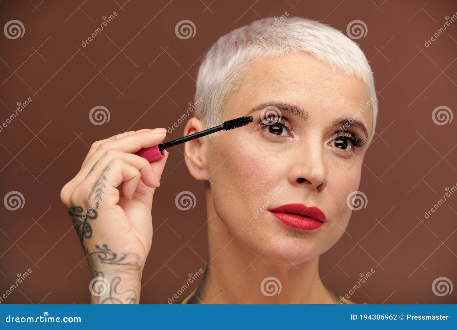 Mature Woman with Short Blond Hair Applying Black Mascara on Her