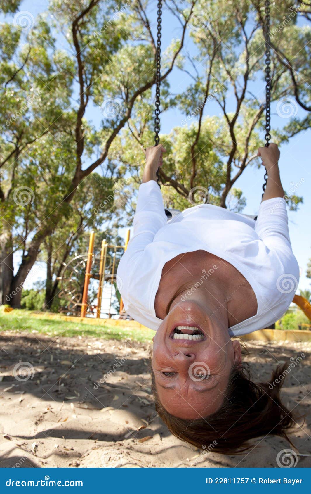 Mature Woman Swinging on Playground Upside Down Stock Image pic