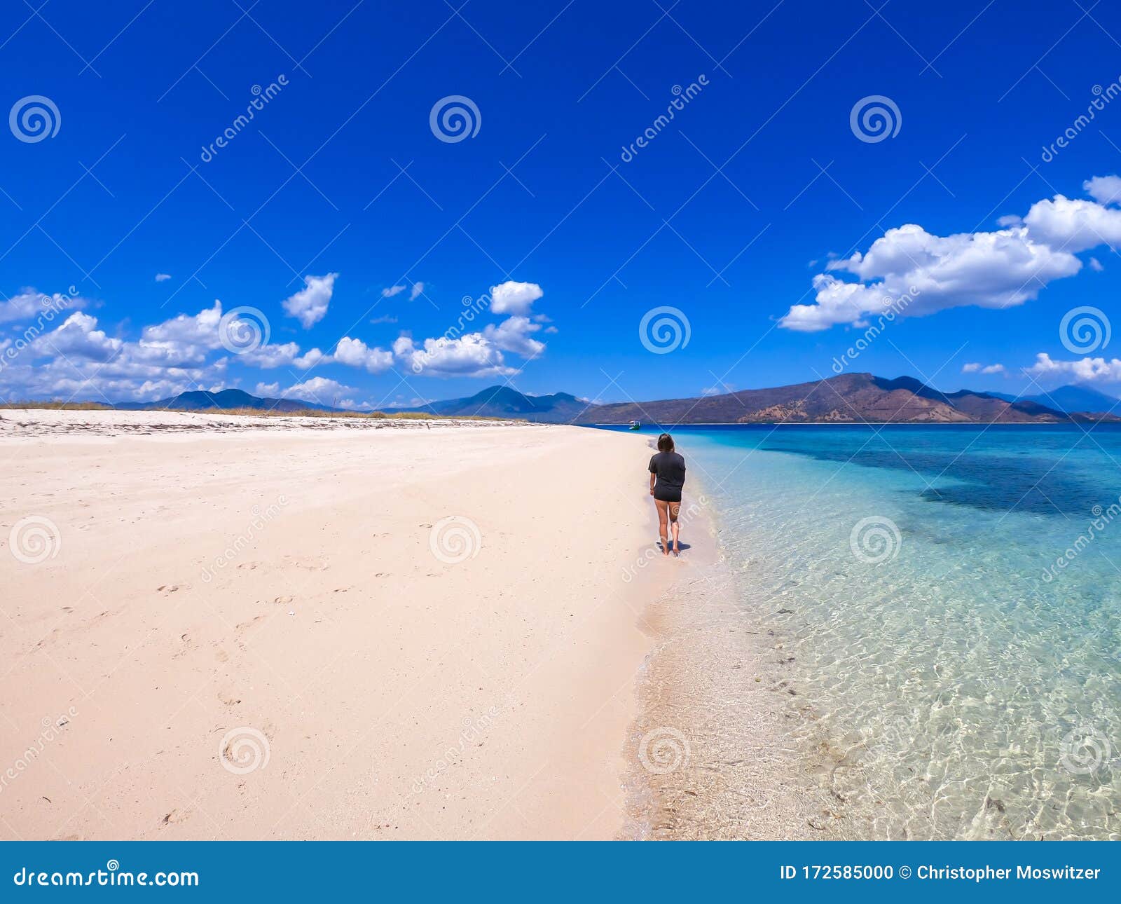 maumere - a girl in black t-shirt walking on the beach
