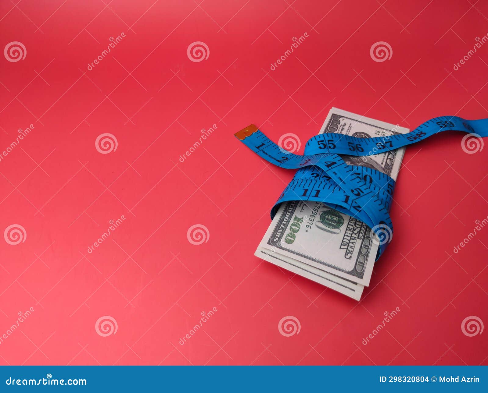 Measuring Tape Wrapped Around Dollar Bills on a Red Background Stock
