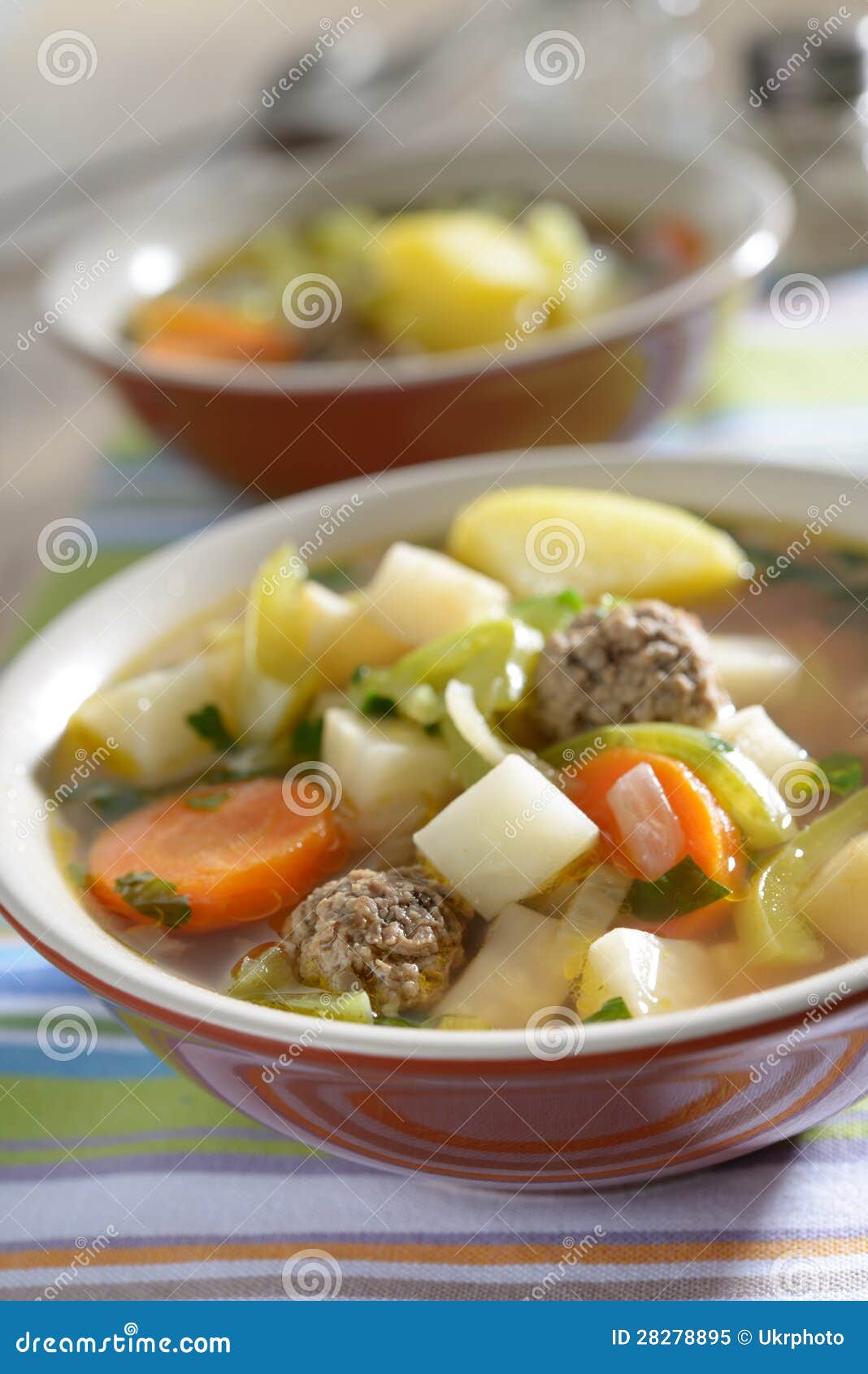 Meatball soup with vegetables on a rustic table