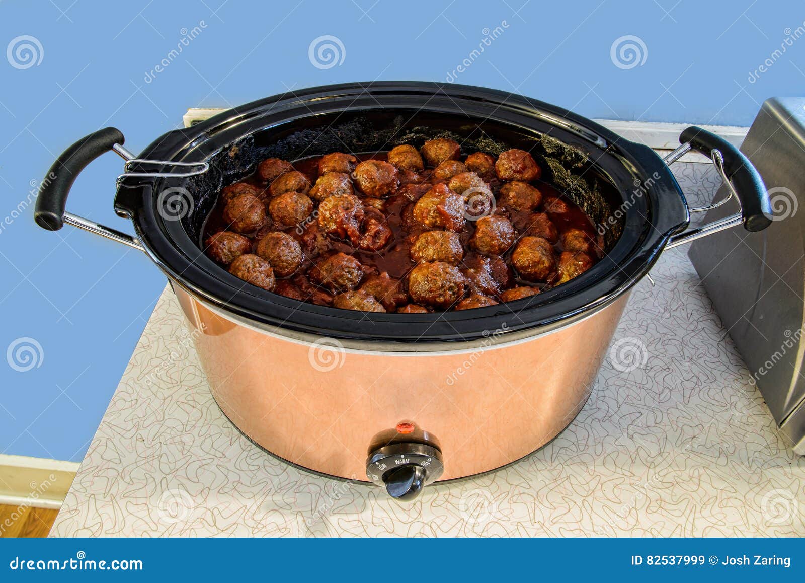 meatballs in stainless crock pot slow cooker on counter