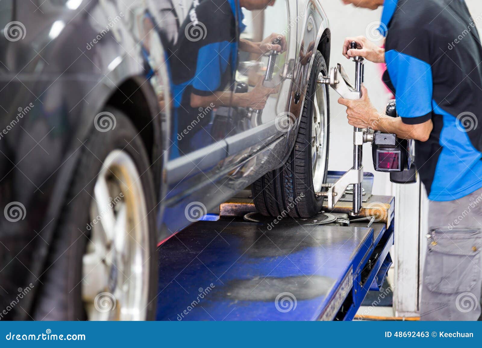 mechanic attaching the wheel alignment device onto the wheel at workshop