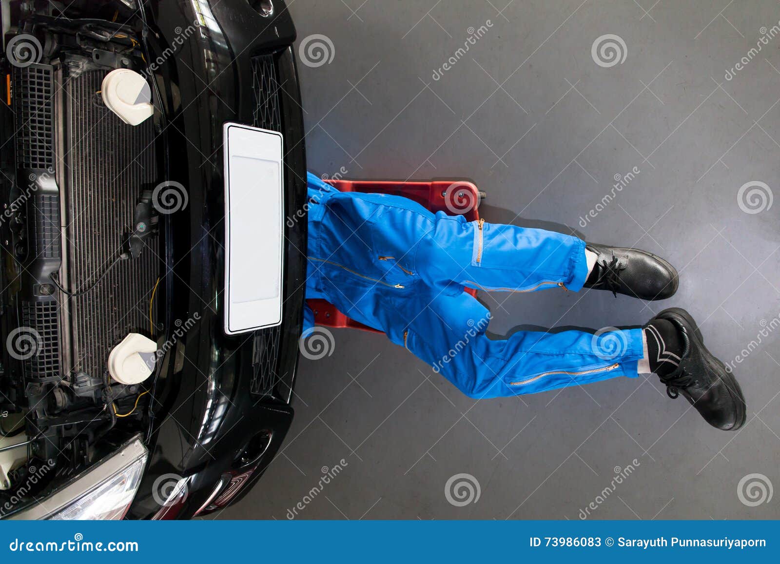 Mechanic In Blue Uniform Lying Down And Working Under Car At T