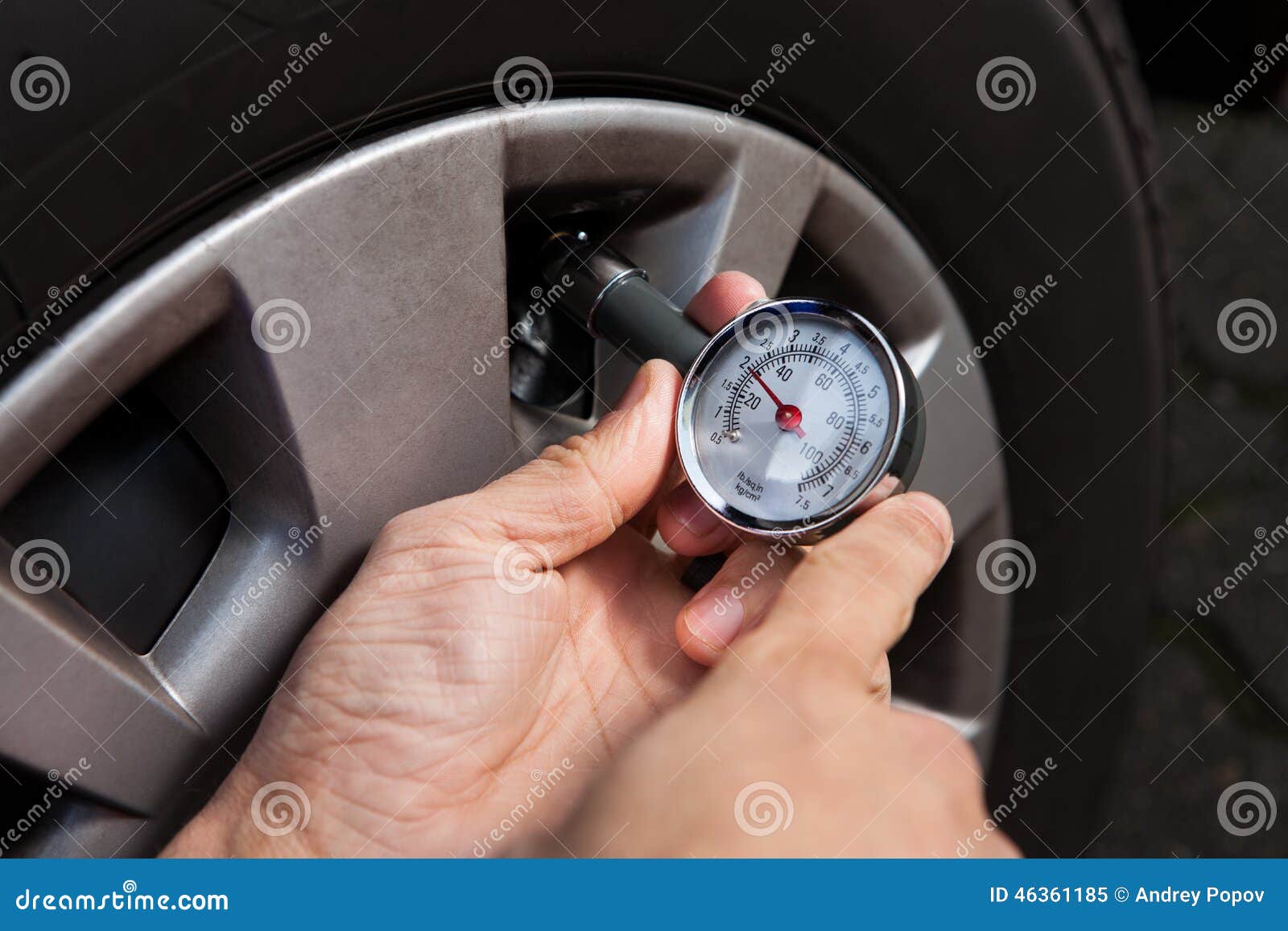 mechanic checking tire pressure using gauge