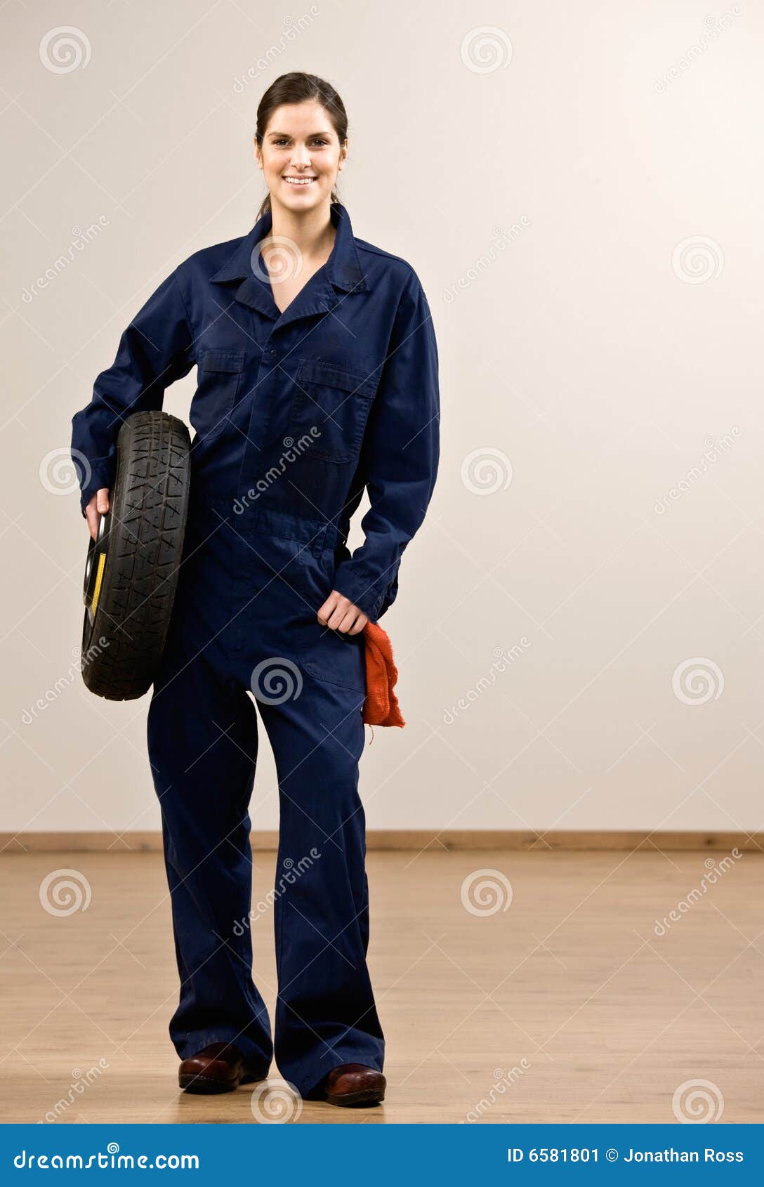 mechanic in coveralls holding tire