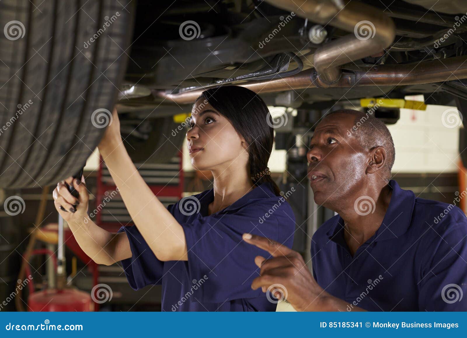 mechanic and female trainee working underneath car together