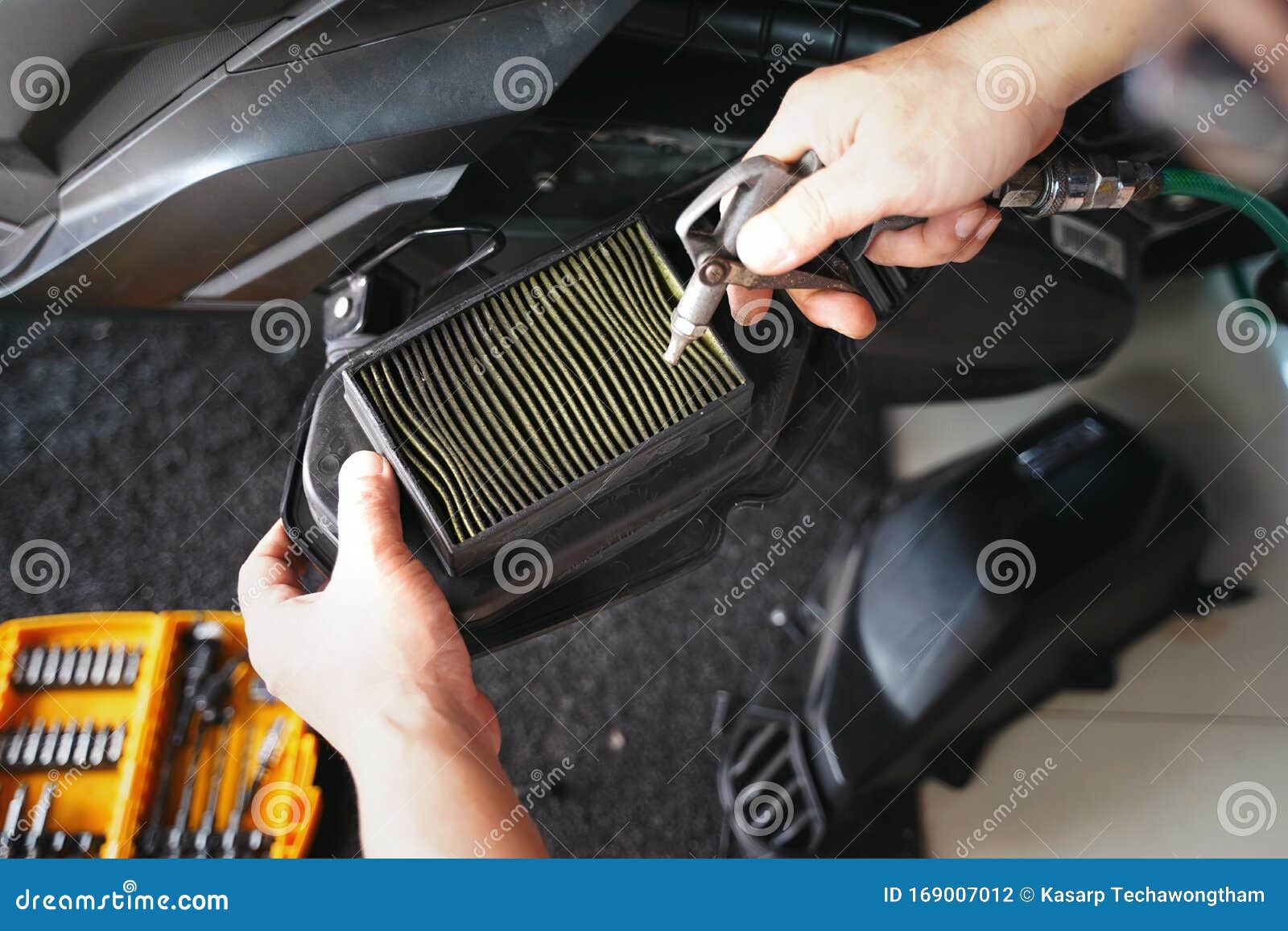 Mechanic Holding Dirty Engine Air Filter Over Big Scooter And Cleaning