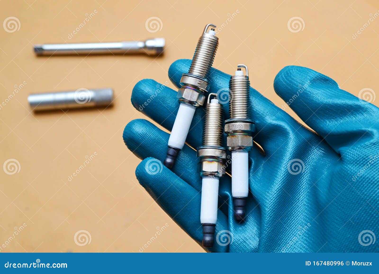 mechanic holding three spark plugs in hand