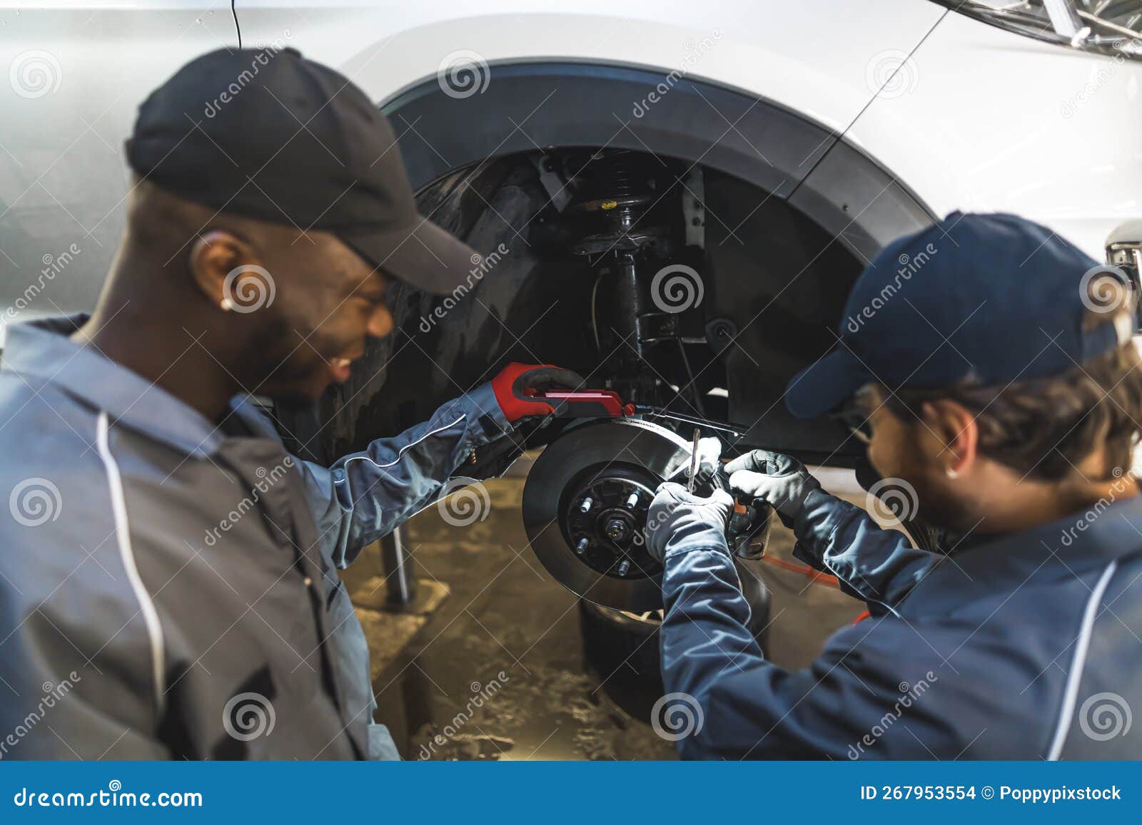Mechanic Replacing Wheels of White Luxury Car Using Tools in an Auto