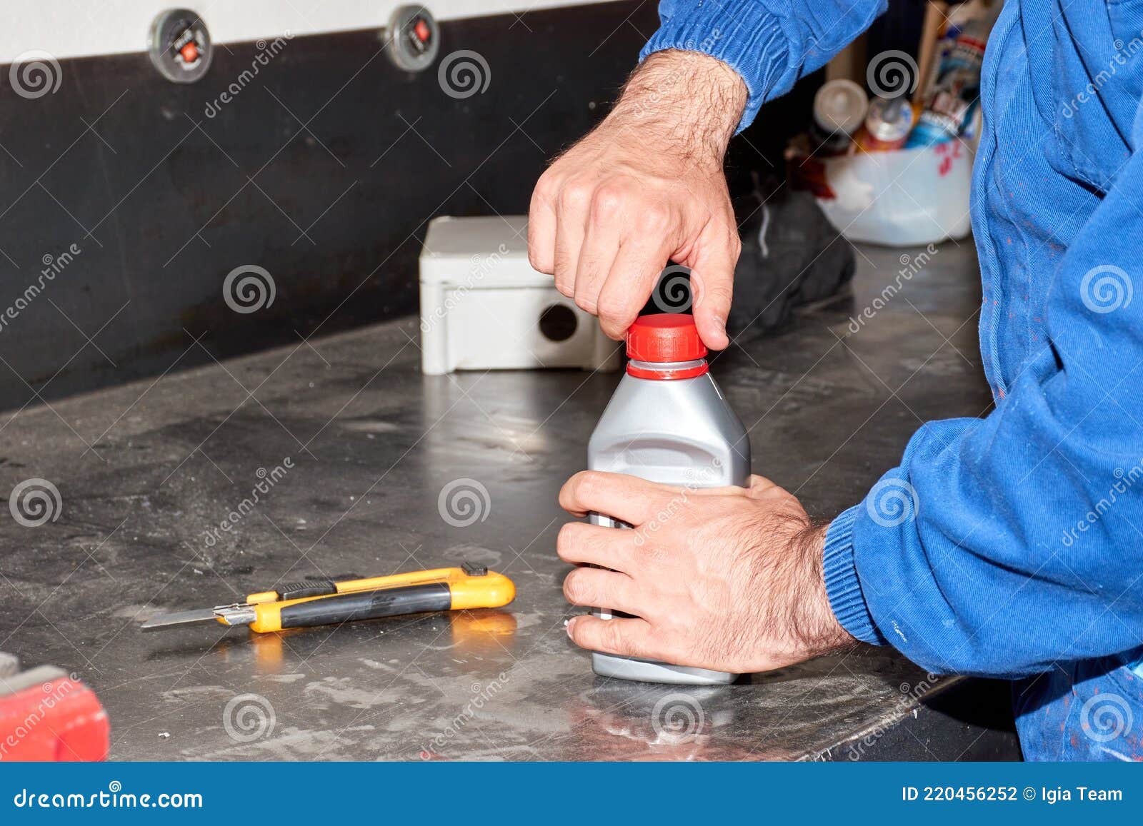 Mechanic Unscrewing the Cap of a Plastic Bottle Containing Brake Fluid