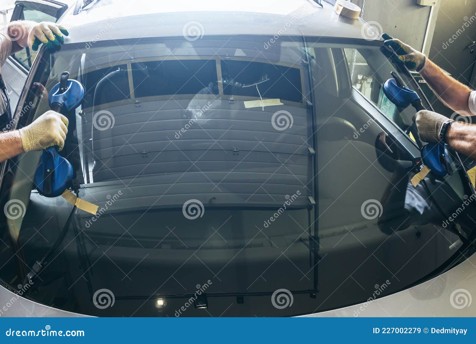 mechanic workers hands changes broken windscreen on new windshield on car in service station close up