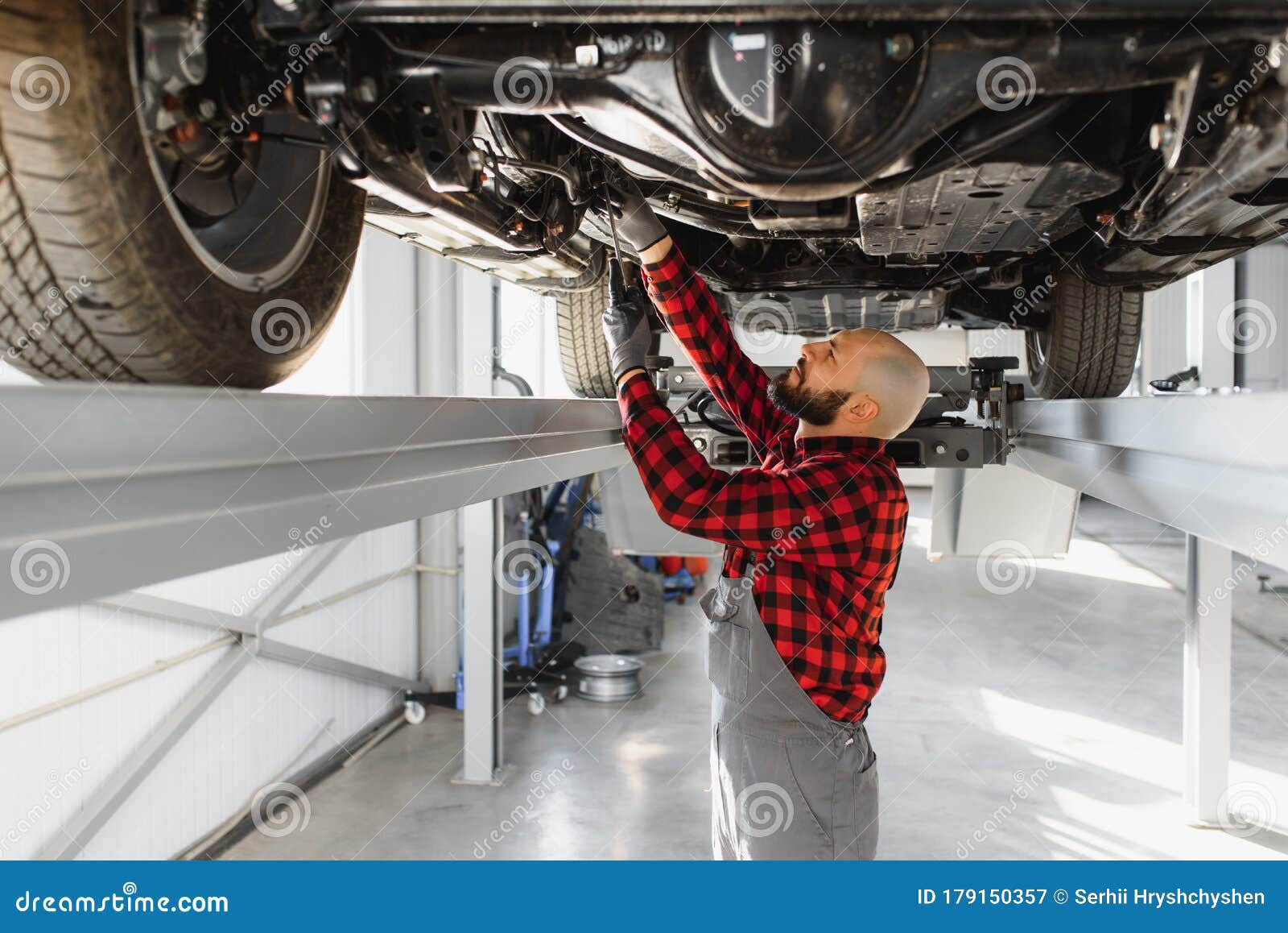 Mechanic Working Under Car At The Repair Garage. Auto Mechanic Working