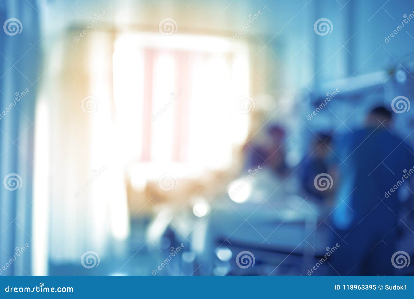 medical workers at the patient`s bed in a sunlit room, unfocused