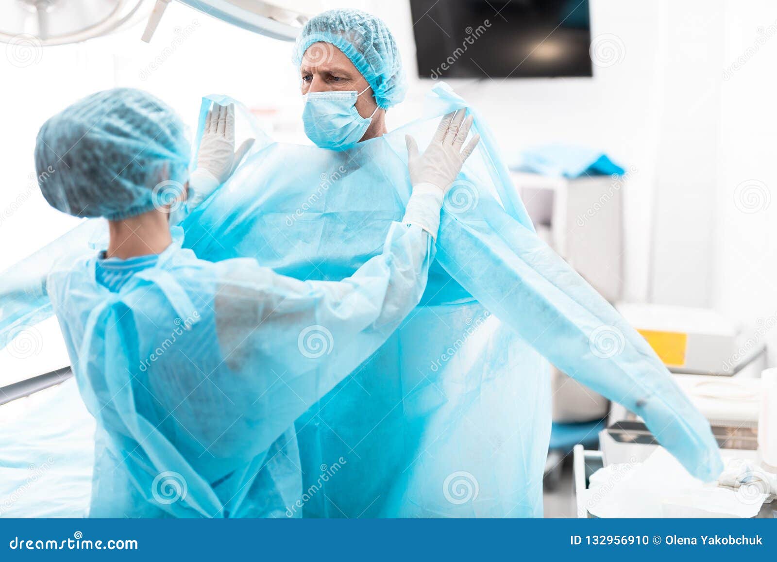 assistant helping surgeon to prepare for surgical operation