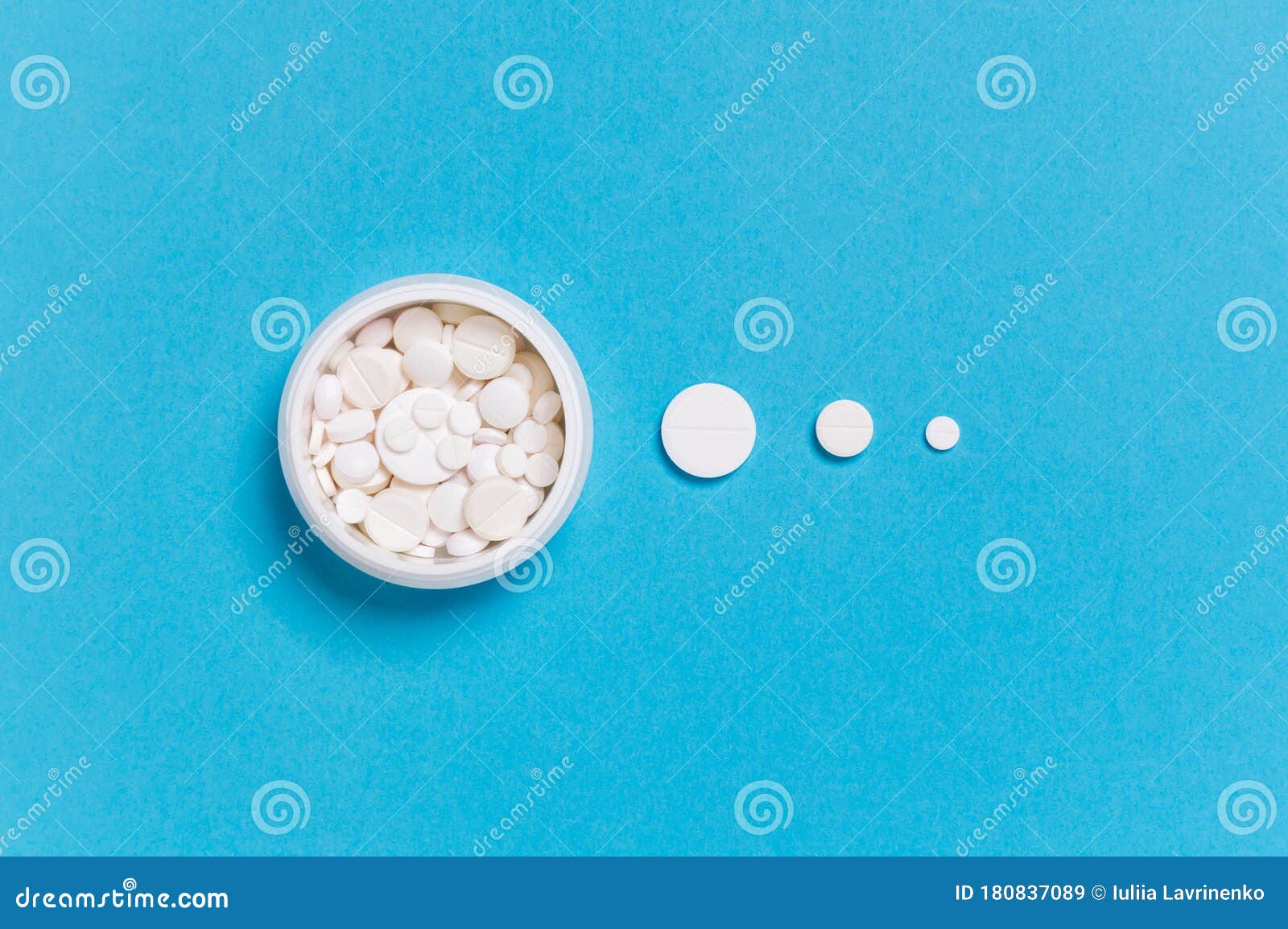 medicine bottle with white pills and dosis of different size drugs on blue background