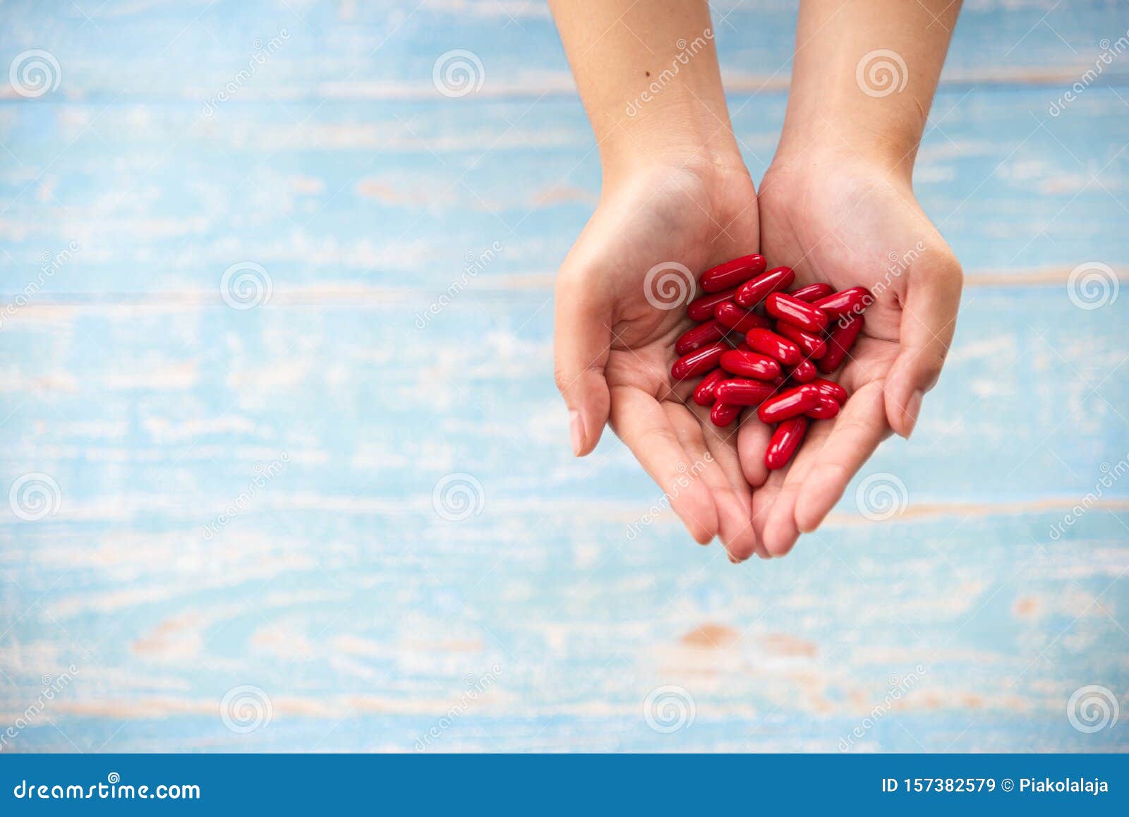 medicine, healthcare, concept. closed up hands hold the red medicines or vitamines on the wooden background