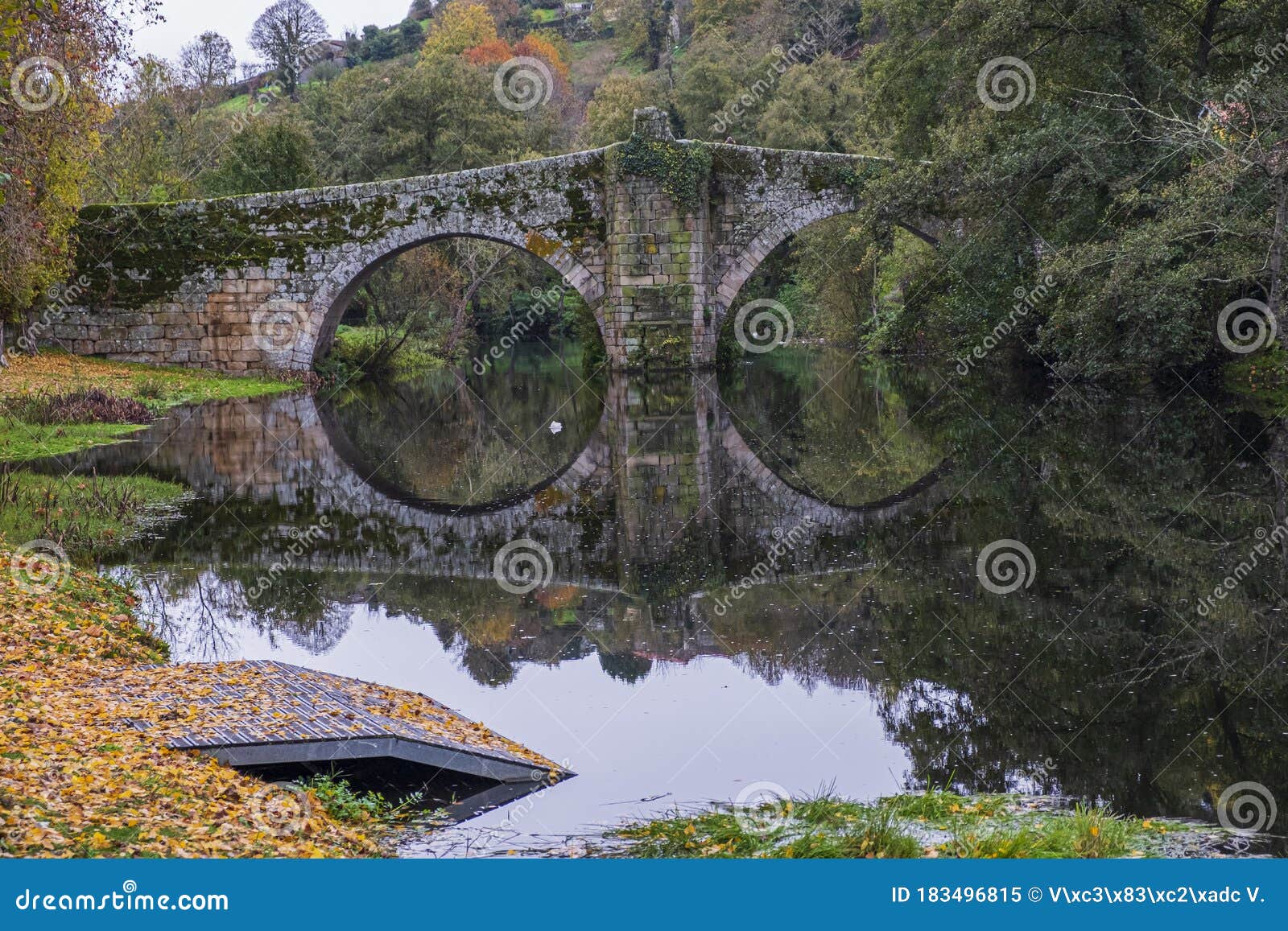 fall foliage and medieval roman bridge reflected on the river arnoia in the galician village of allariz, ourense. spain.