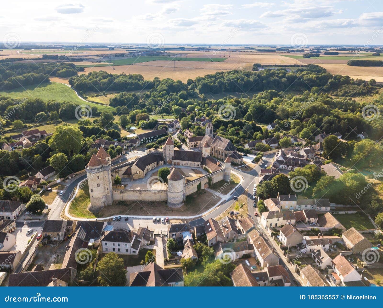 medieval castle with fortified walls, towers and donjon in rural village in france, aerial view from drone of renovated fortress